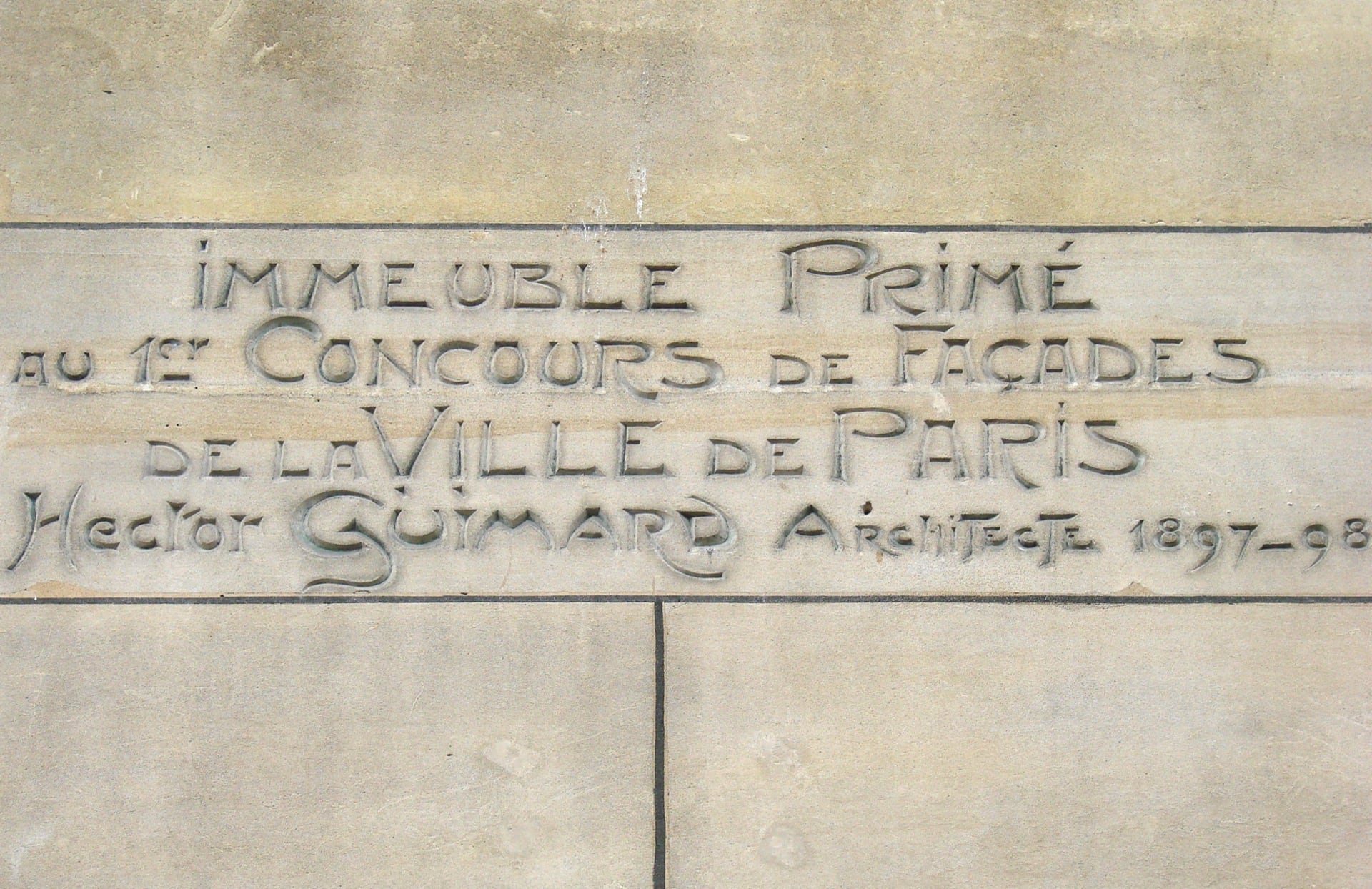 Plaque gravée en façade du Castel Béranger : « Immeuble primé au 1er concours de façades de la Ville de Paris, Hector Guimard architecte 1897-98 », en lettres Art nouveau