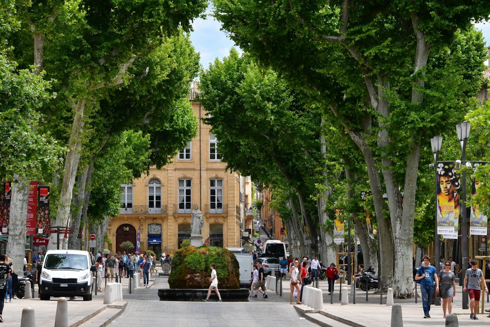 Le cours Mirabeau à Aix-en-Provence sous son tunnel de platanes, une fontaine moussue au centre de la chaussée