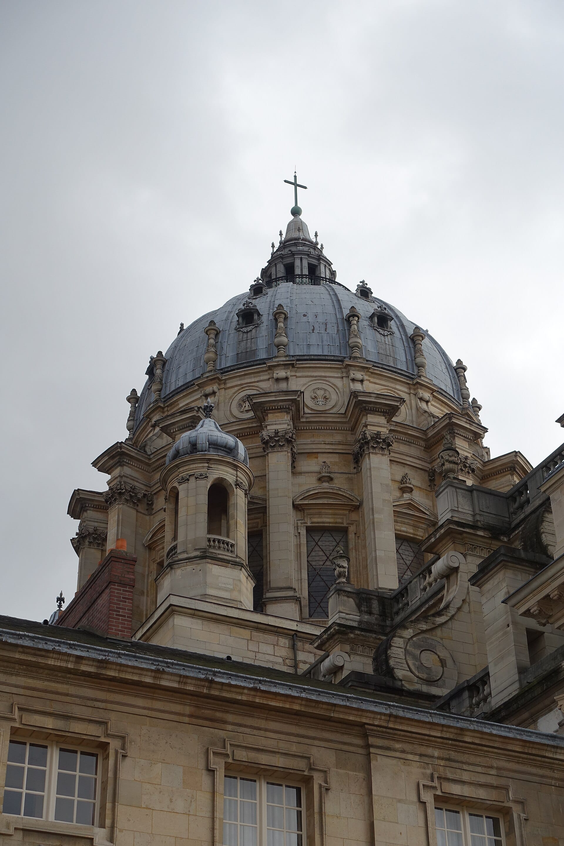 Le dôme extérieur de l’église du Val-de-Grâce vu en contre-plongée : tambour à colonnes accouplées, coupole de plomb à côtes, lanternon surmonté d’une croix