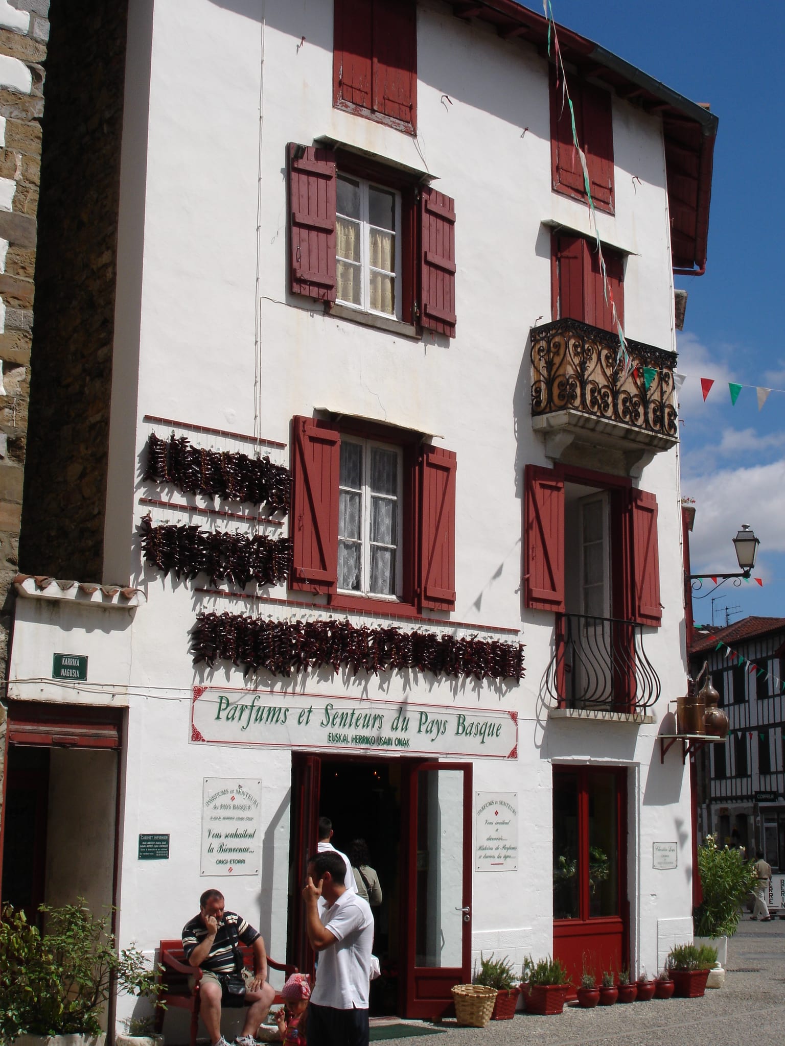 Cordes de piments d’Espelette suspendues à sécher sur une façade à colombage rouge