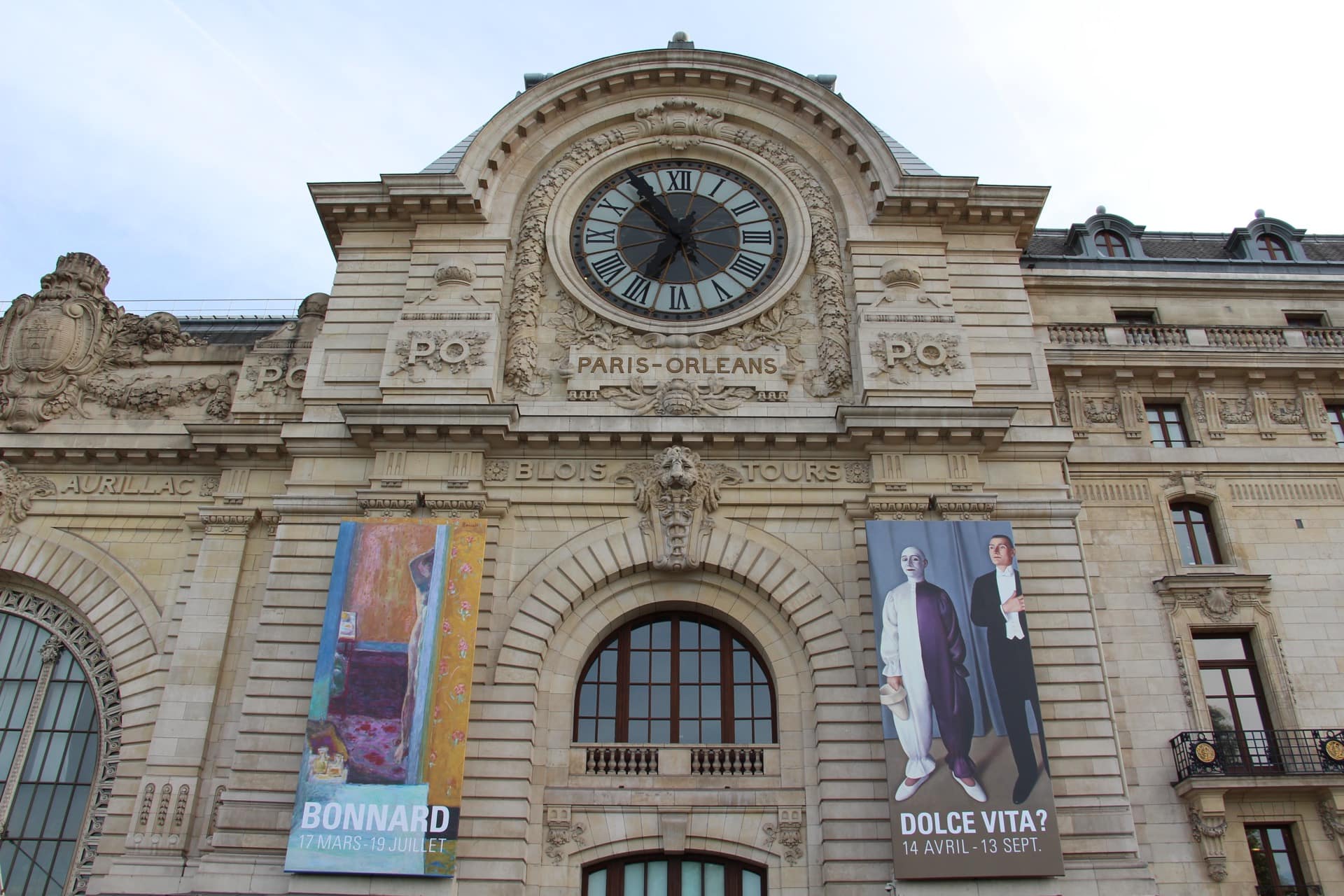 La façade de l’ancienne gare d’Orsay, aujourd’hui musée d’Orsay, en contre-plongée : grande horloge, inscription « Paris-Orléans » et noms de villes desservies, grand arc vitré