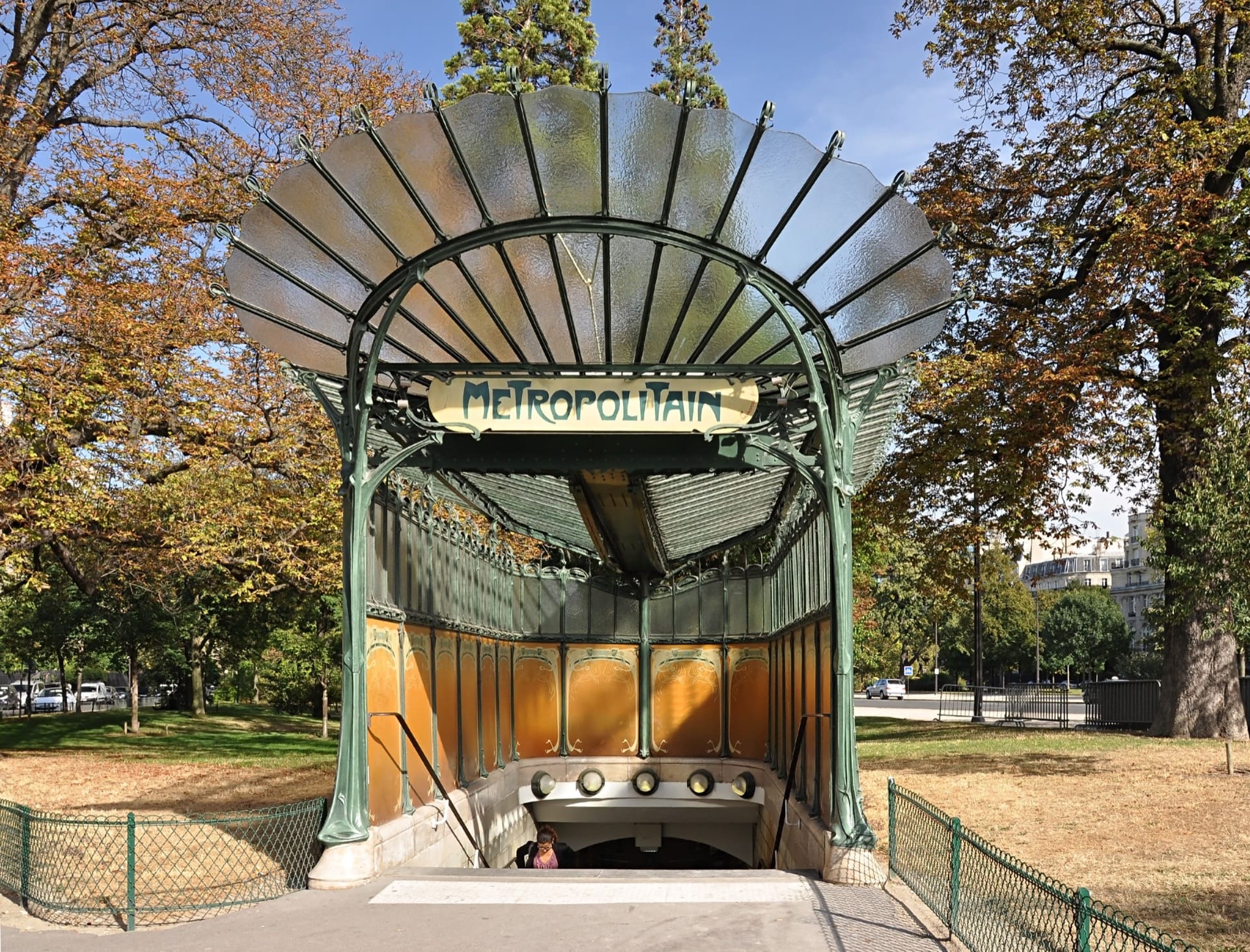 L’édicule du métro Porte Dauphine par Hector Guimard : marquise en éventail de verre et de fonte vert d’eau, enseigne « Métropolitain » en lettres Art nouveau, dans un cadre de verdure