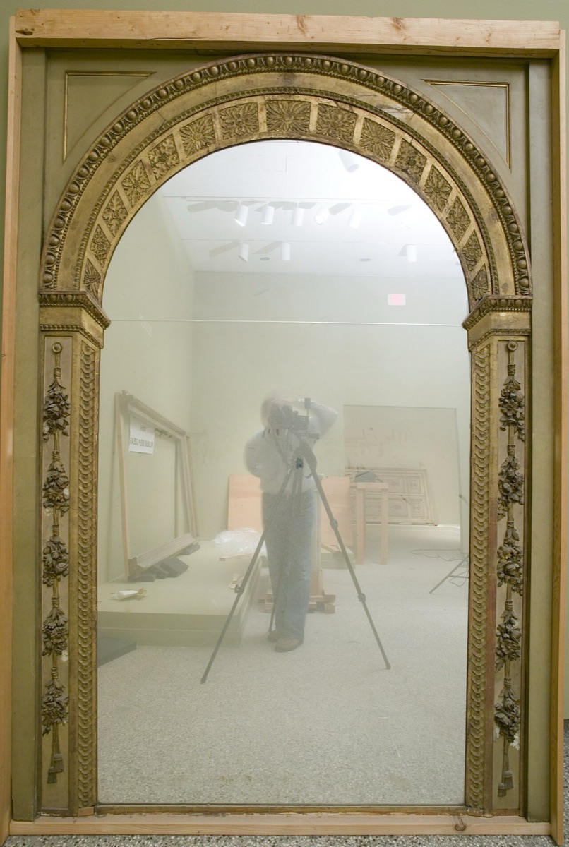 Trumeau de cheminée français du XVIIIᵉ siècle : une glace verticale surmontée d’une toile peinte, le tout encadré d’une boiserie sculptée et moulurée.