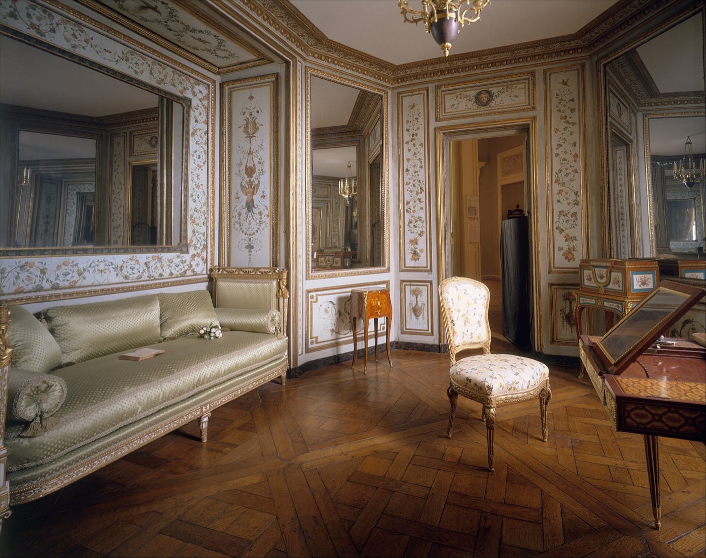 Boudoir français du XVIIIᵉ siècle déposé et remonté en salle de musée : boiseries sculptées et peintes couvrant les murs d’une petite pièce ovale, reconstituée derrière une cloison muséale.