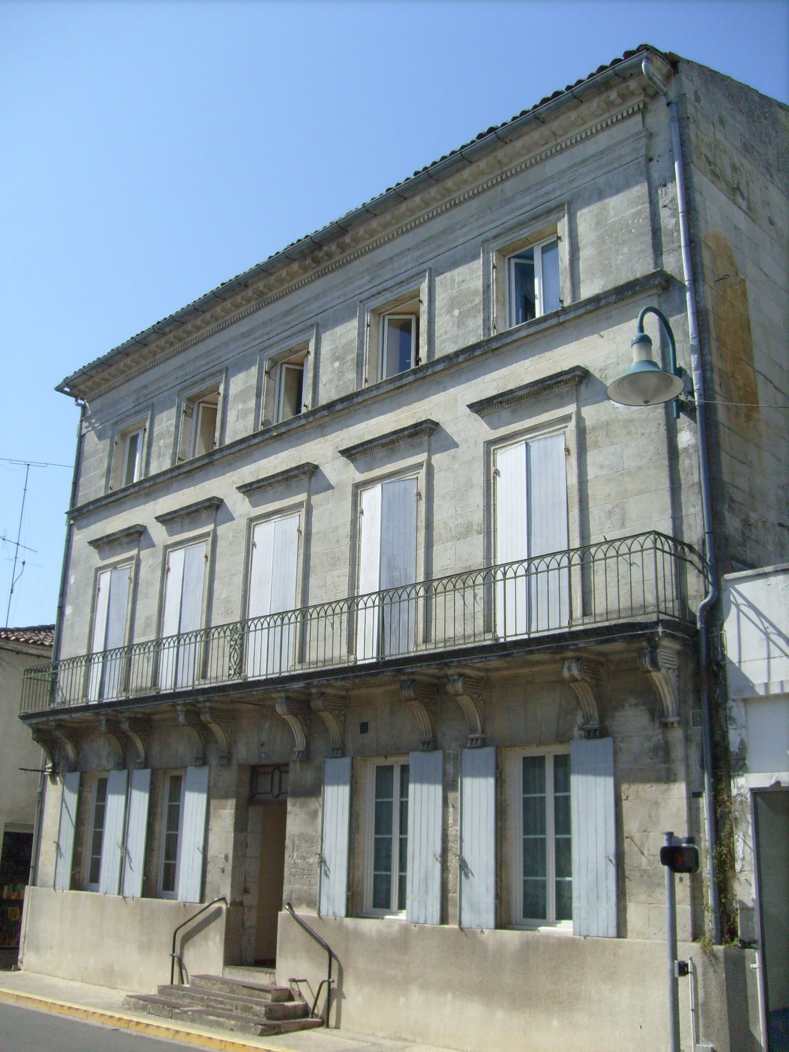 Maison de maître à étage en pierre de taille claire, façade ordonnancée à balcon, à Gémozac
