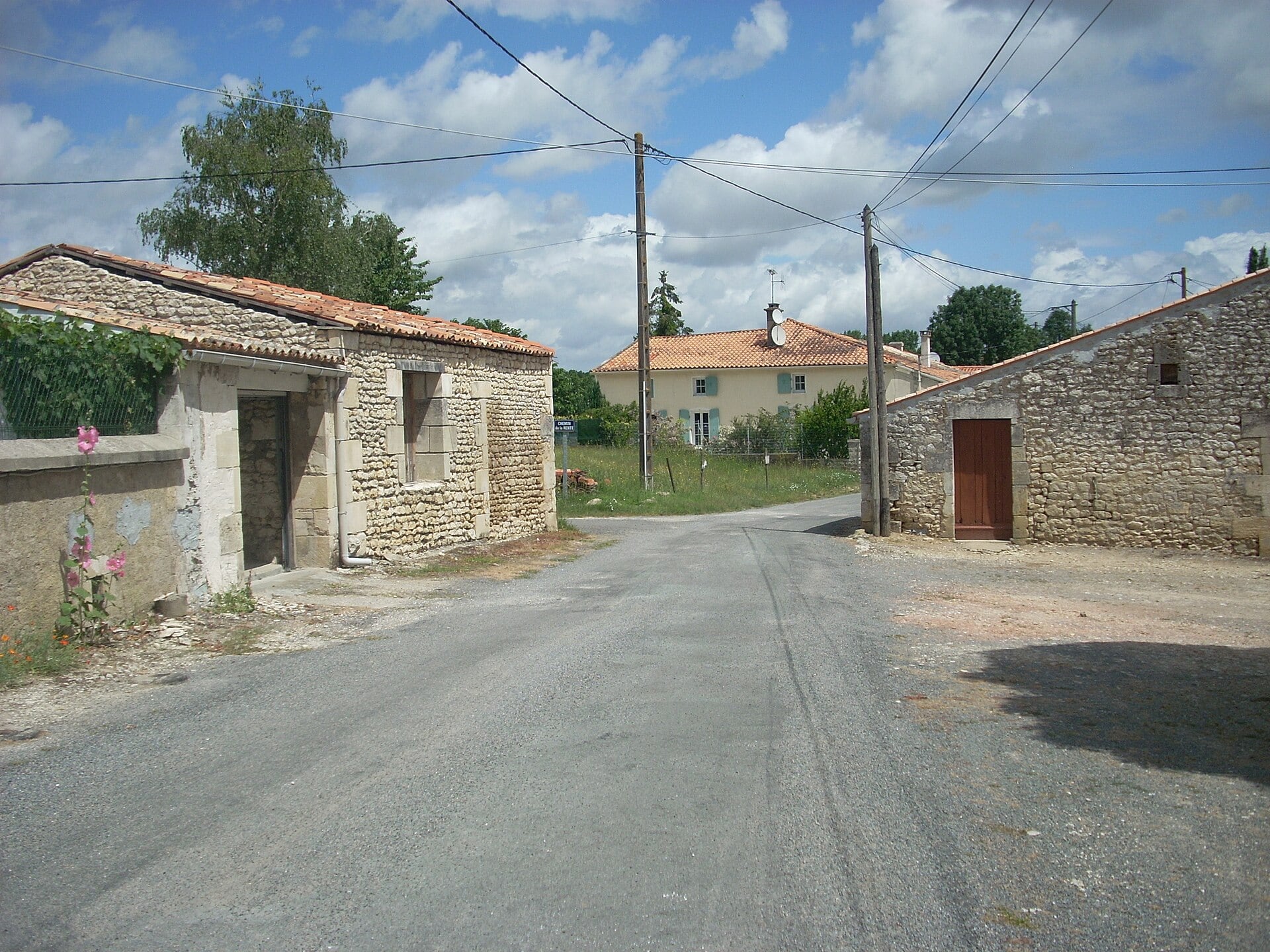 Portail de pierre fermant une cour, entre des maisons basses à toits de tuiles, en Charente