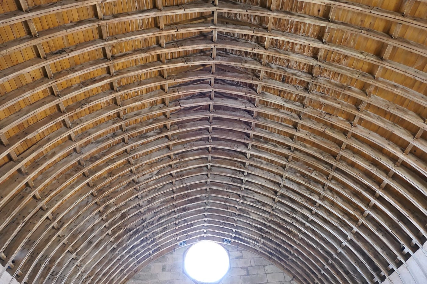 Charpente construite selon le procédé de Philibert de l’Orme : arcs formés de courtes planches de bois cintrées, boulonnées et superposées.