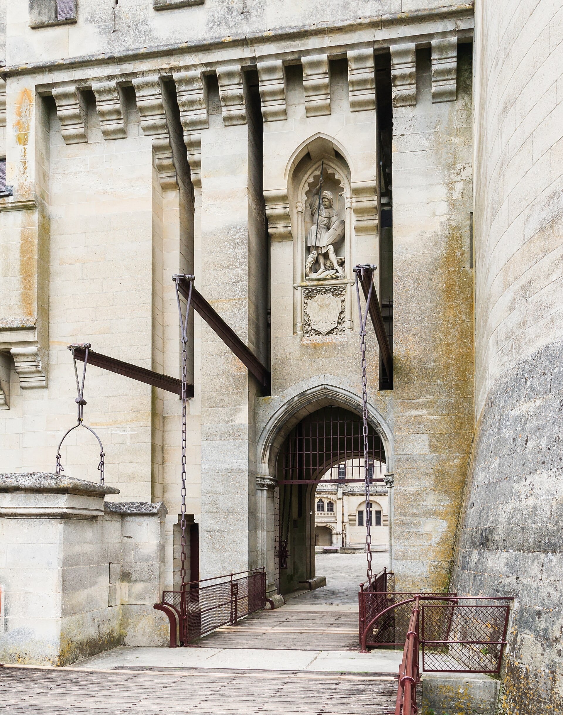 Détail du pont-levis de Pierrefonds : chaînes de levage, arc brisé, mâchicoulis en encorbellement, niche à statue de chevalier
