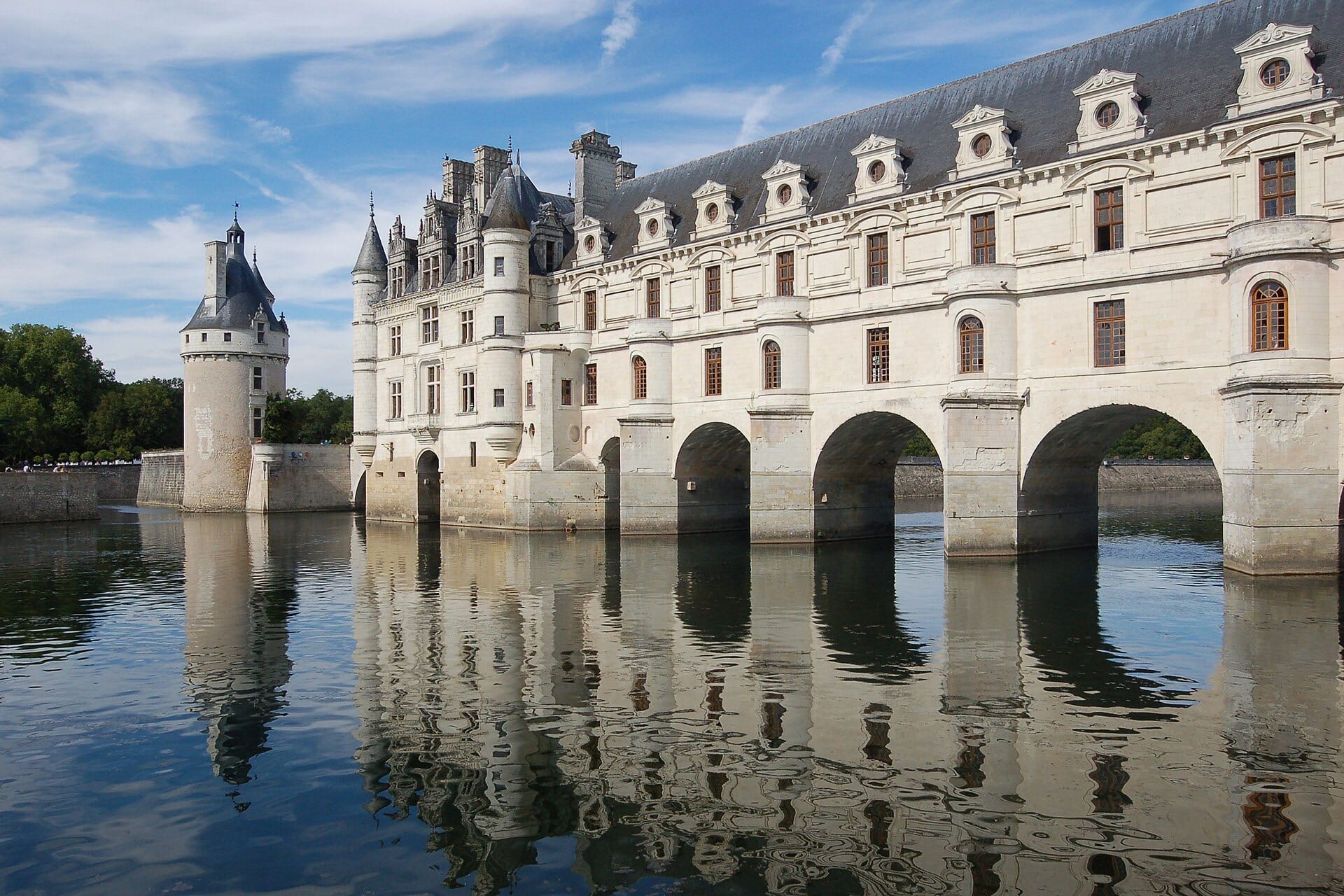 Château de Chenonceau enjambant le Cher : galerie à deux étages posée sur cinq arches, tour ronde des Marques à gauche, hauts combles d’ardoise à lucarnes