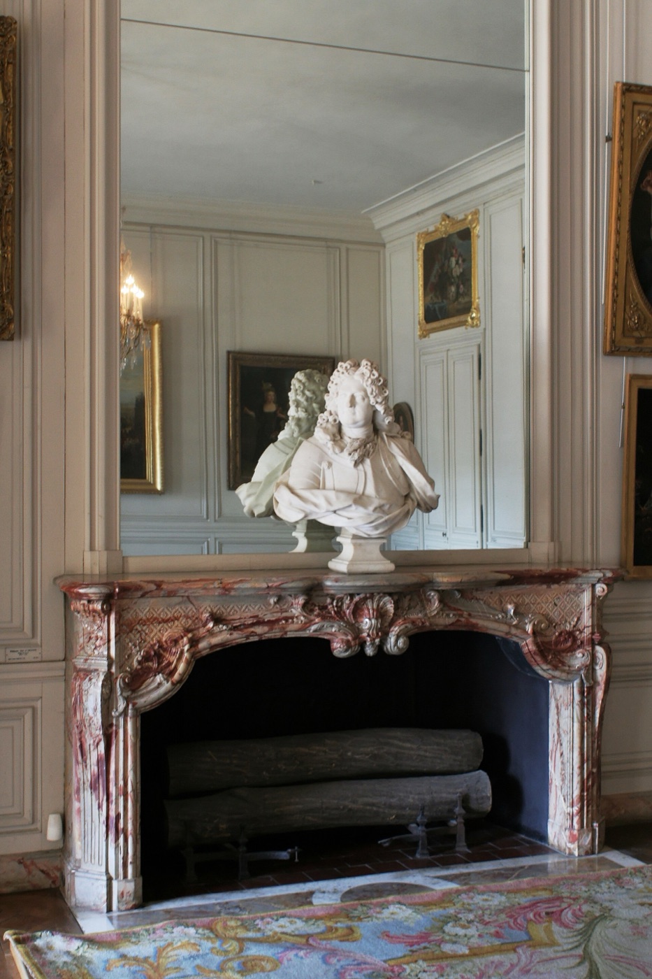 Cheminée classique en marbre à manteau bas surmonté d’un trumeau à glace, encadrée de boiseries, dans un appartement du XVIIIᵉ siècle à Versailles.