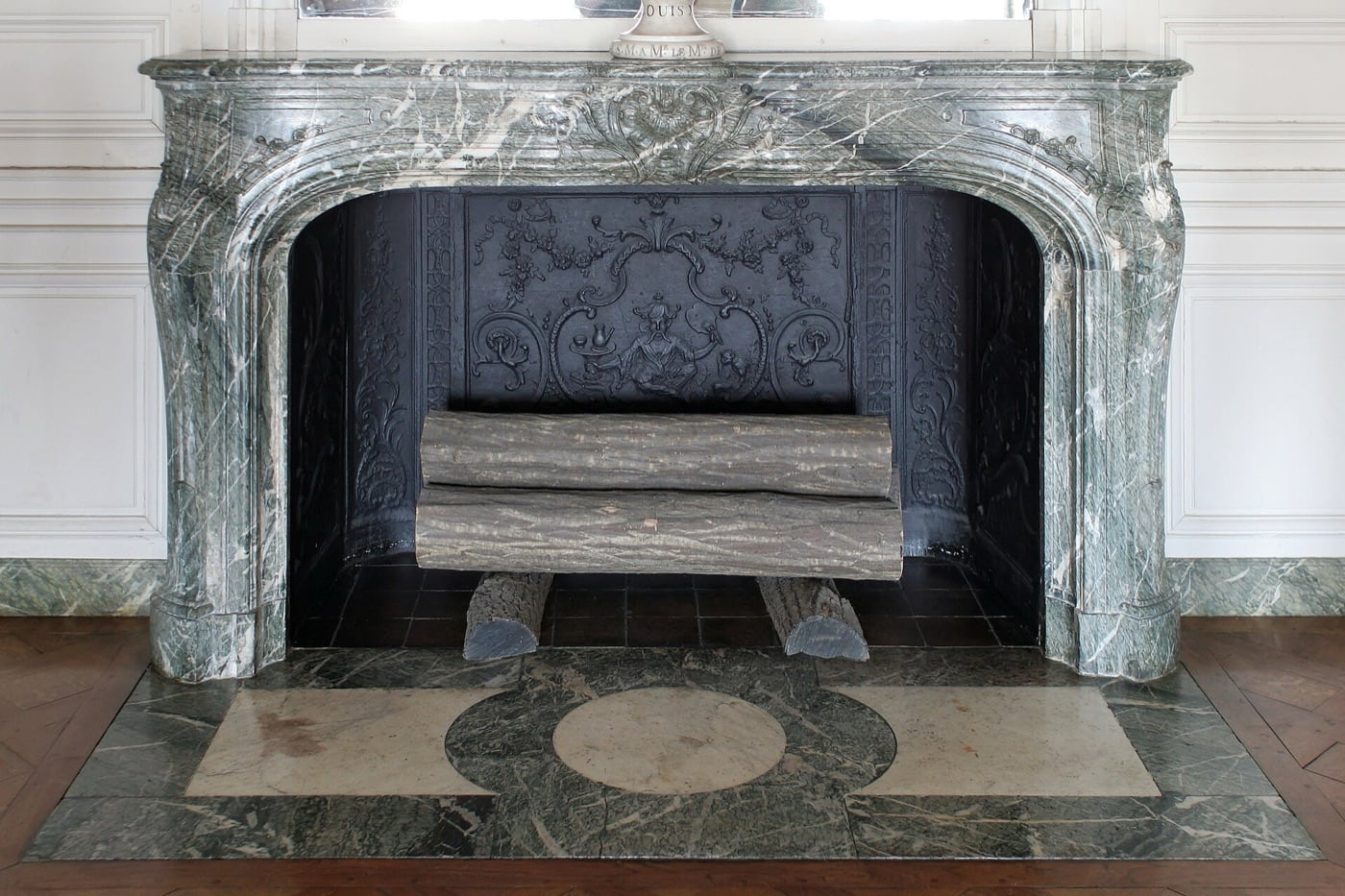 Cheminée du XVIIIᵉ siècle en marbre vert veiné, à manteau bas mouluré, dans un appartement du château de Versailles.
