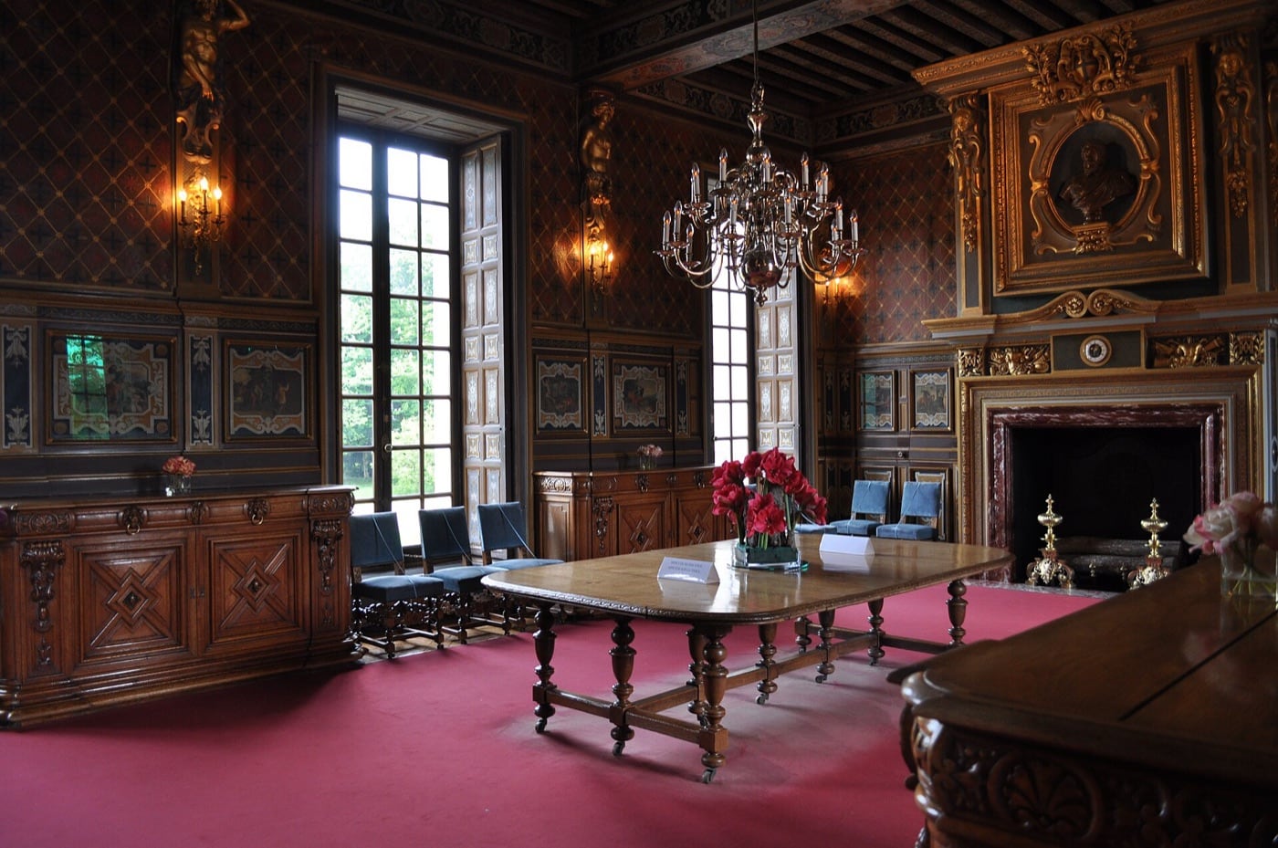 Salle classique du château de Cheverny : cheminée dorée intégrée aux boiseries peintes, sous les dessus-de-porte et les décors de la pièce.