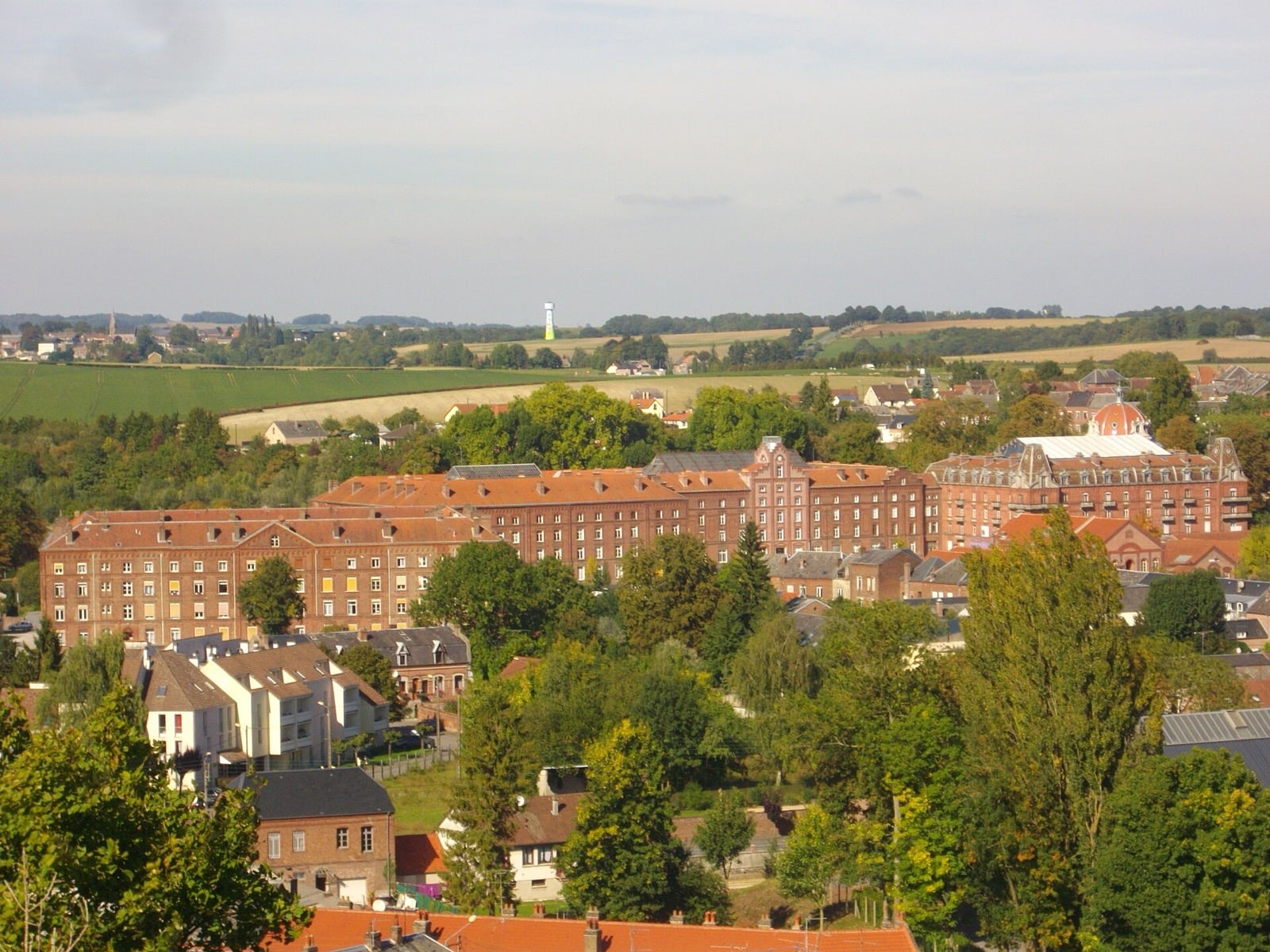 Vue élevée du Familistère de Guise et des ateliers voisins avec leurs cheminées, depuis une colline