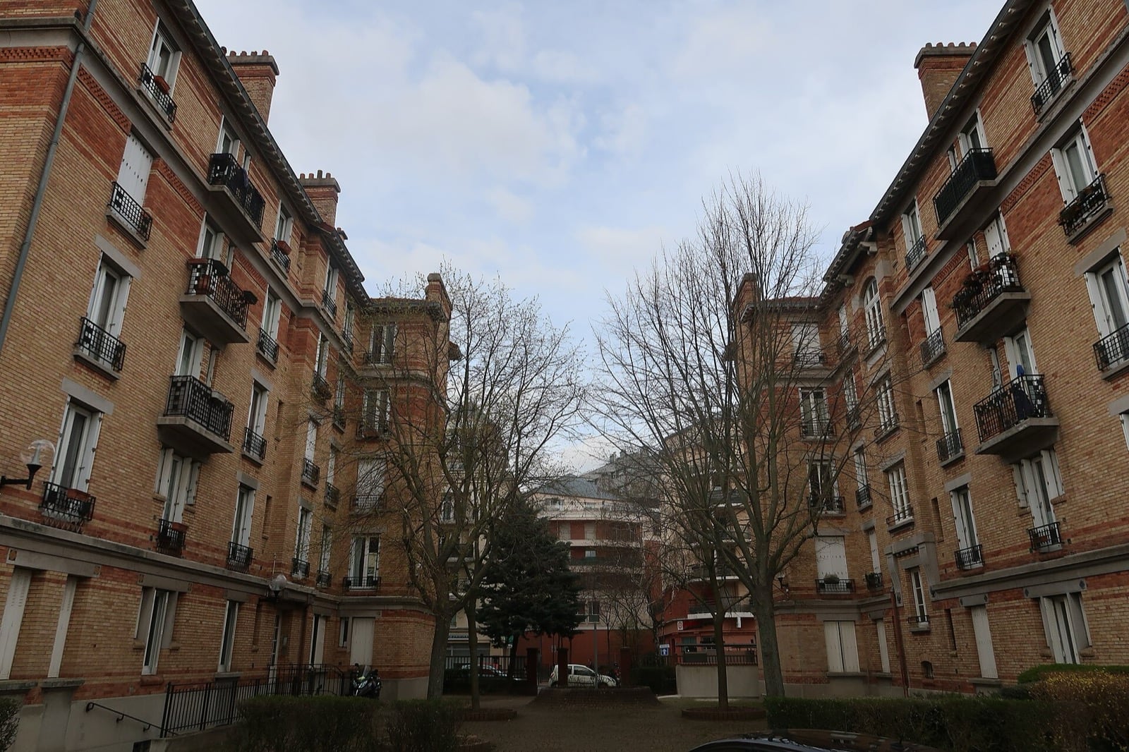 Cour verdoyante entre deux immeubles de brique à balcons de la cité-jardin de Suresnes