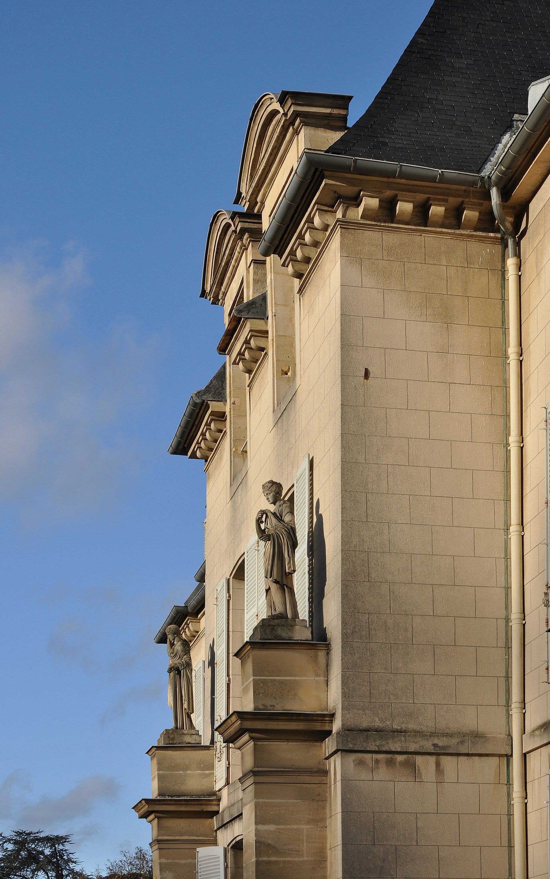 Détail de l’angle du château de Malmaison : statue en niche, avant-toit à modillons, tourelle et comble d’ardoise