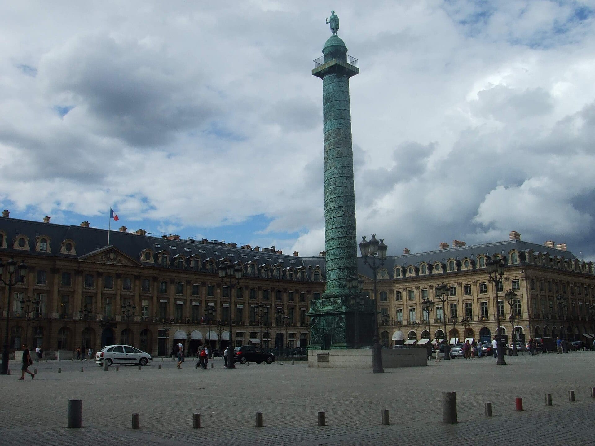 La colonne Vendôme à Paris : haute colonne de bronze à spirale historiée surmontée d’une statue de Napoléon, au centre de la place Vendôme bordée de façades classiques