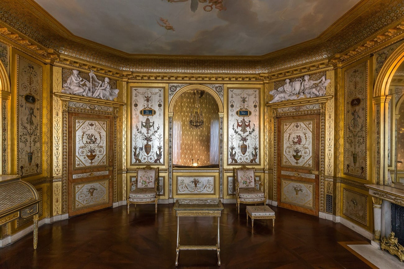 Le boudoir de la Reine à Fontainebleau : petite pièce intime aux murs couverts de boiseries fines à décor d’arabesques, meubles précieux et dimensions resserrées.