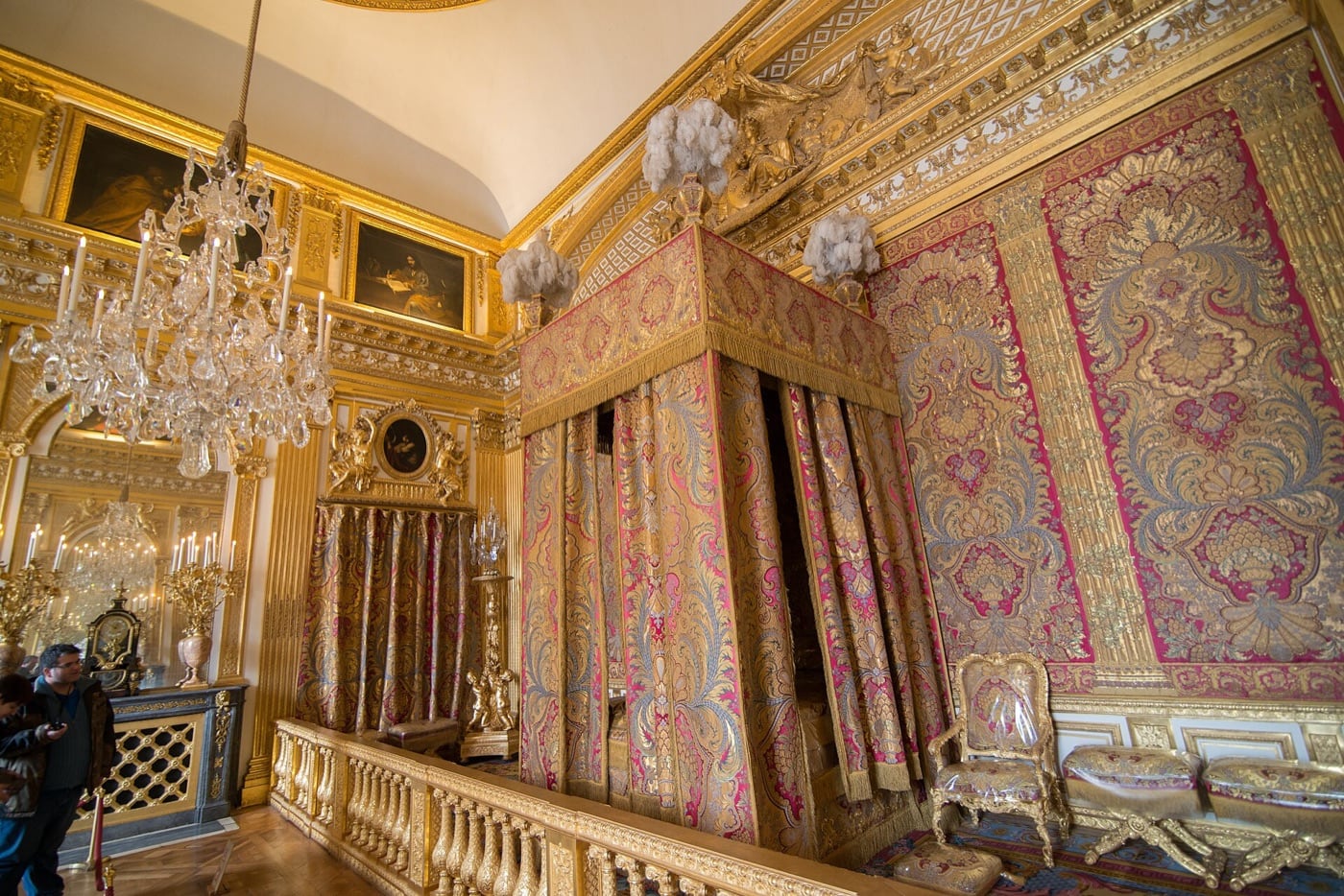 Vue d’un salon du grand appartement du Roi à Versailles : murs de marbre polychrome, plafond peint et doré, ouvrant sur les salons voisins de la file d’apparat.