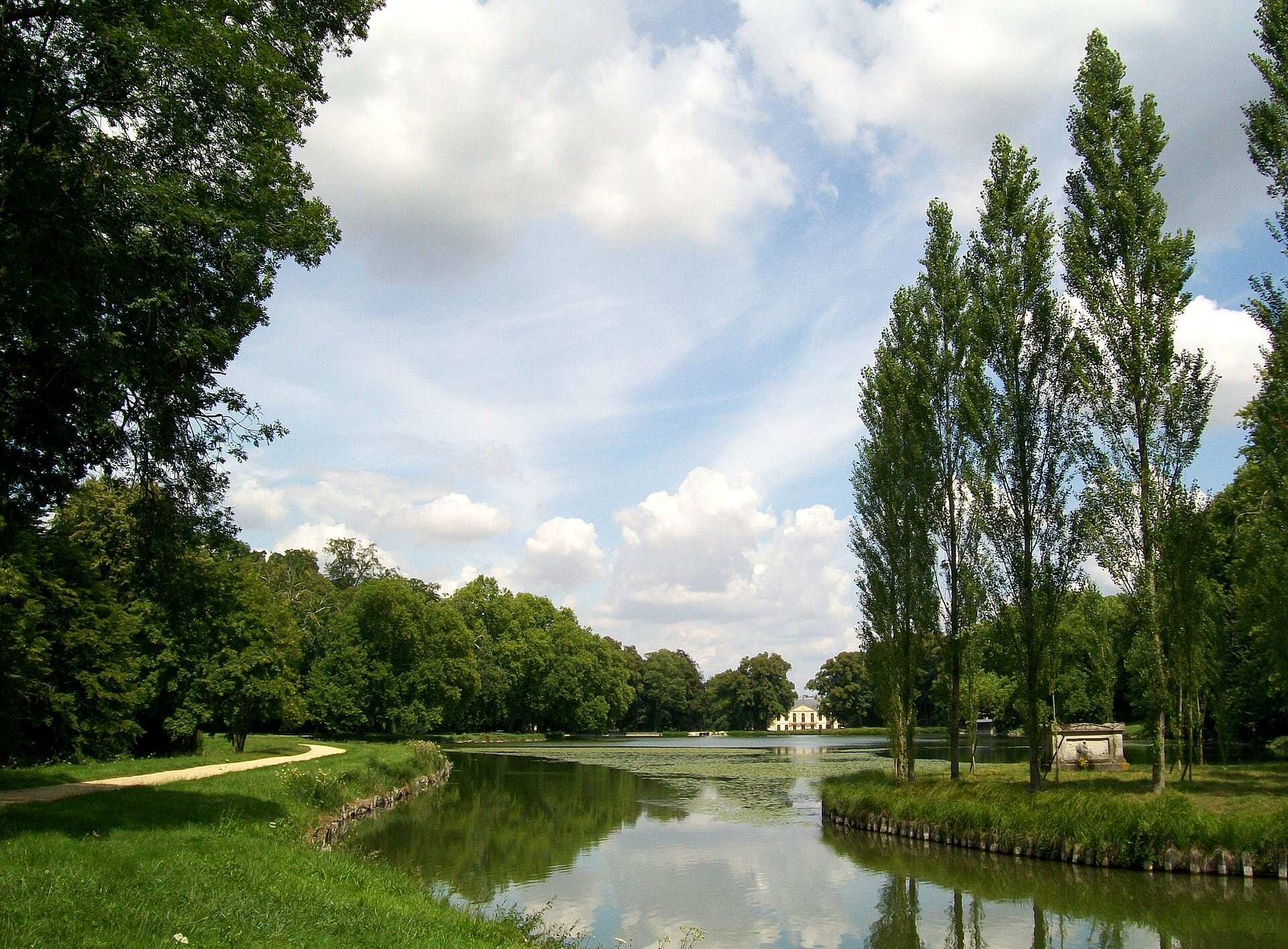 Vue générale du parc d’Ermenonville : plan d’eau sinueux, berges plantées, peupliers de l’île et château dans le lointain, composés en tableau.
