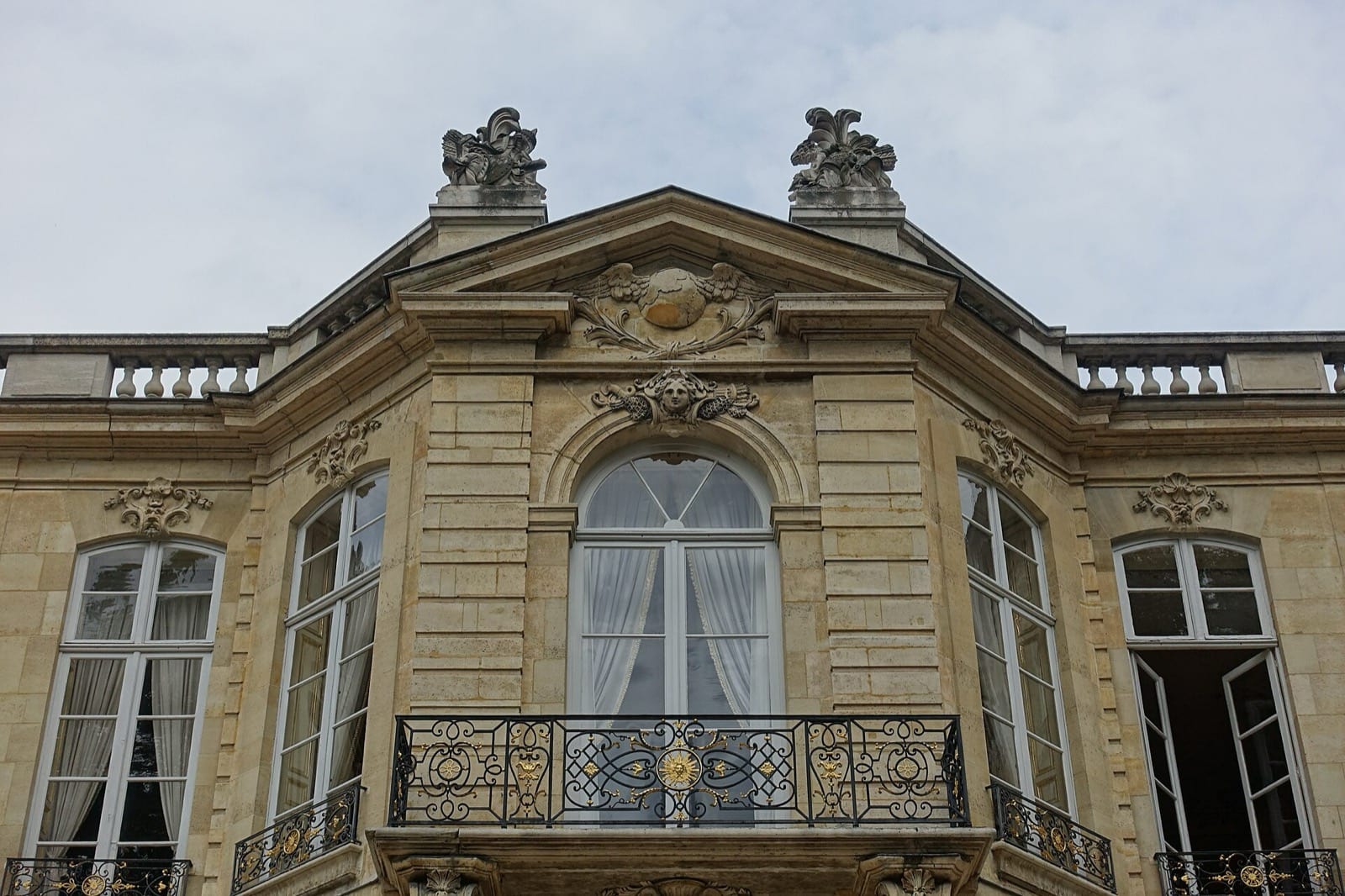 Façade sur jardin de l’hôtel de Matignon à Paris : fronton sculpté, balcon à balustrade de fer forgé doré, portes-fenêtres à petits carreaux