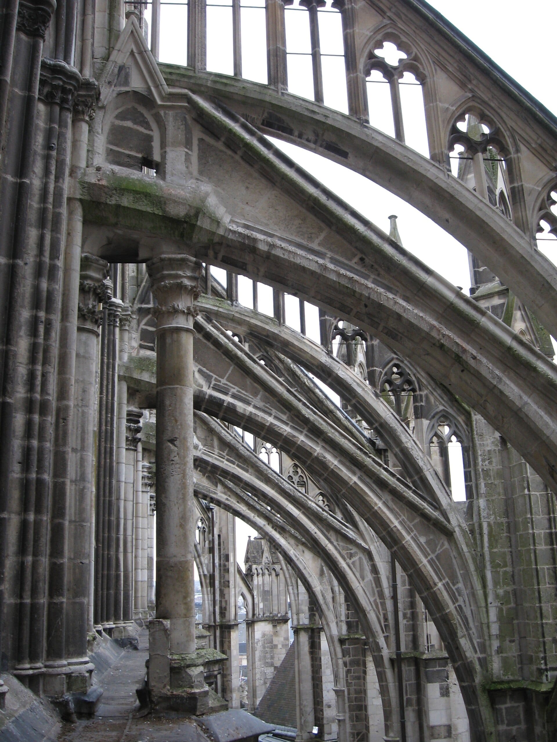 Volée d’arcs-boutants au flanc de la cathédrale d’Amiens : arcs de pierre reportant la poussée des voûtes sur des culées extérieures, remplages ajourés à quatre-feuilles