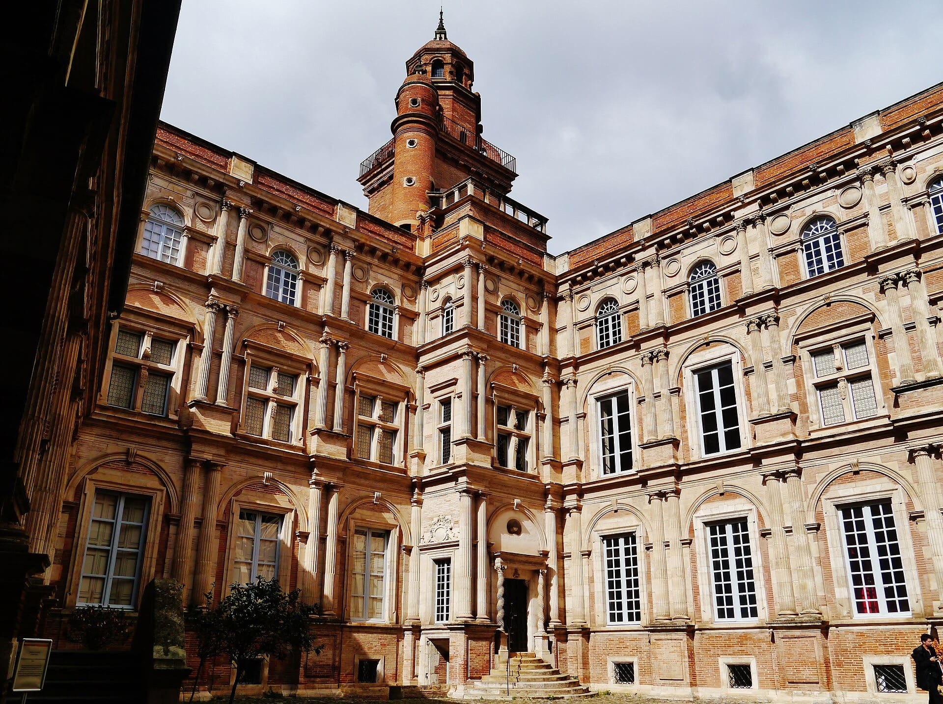 Cour Renaissance de l’hôtel d’Assézat à Toulouse : brique rose et pierre, ordres superposés (dorique, ionique, corinthien), tour d’escalier d’angle