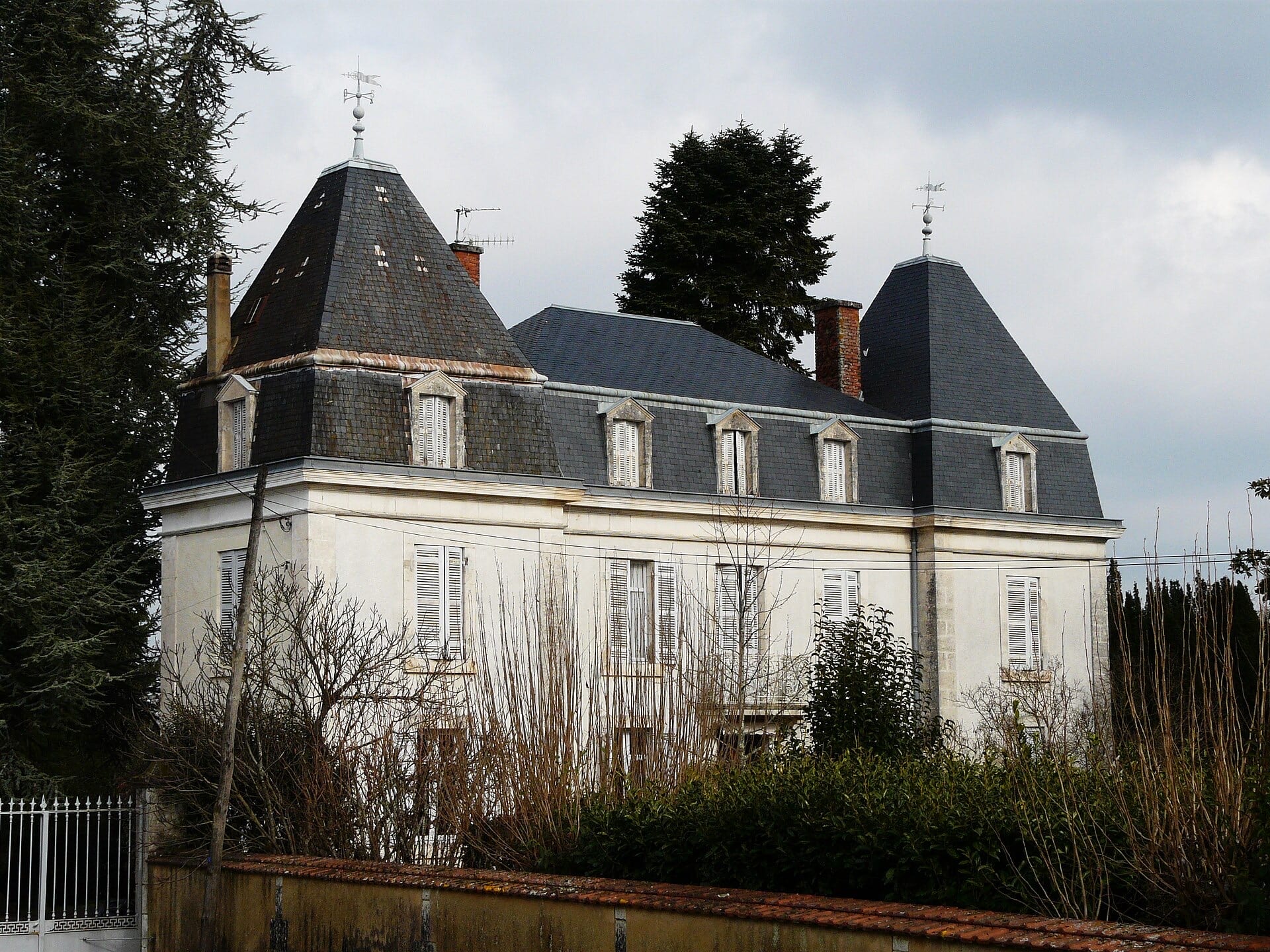 Maison de maître périgourdine enduite claire flanquée de deux pavillons carrés coiffés de toits pyramidaux d’ardoise, toit à lucarnes, encadrements de pierre