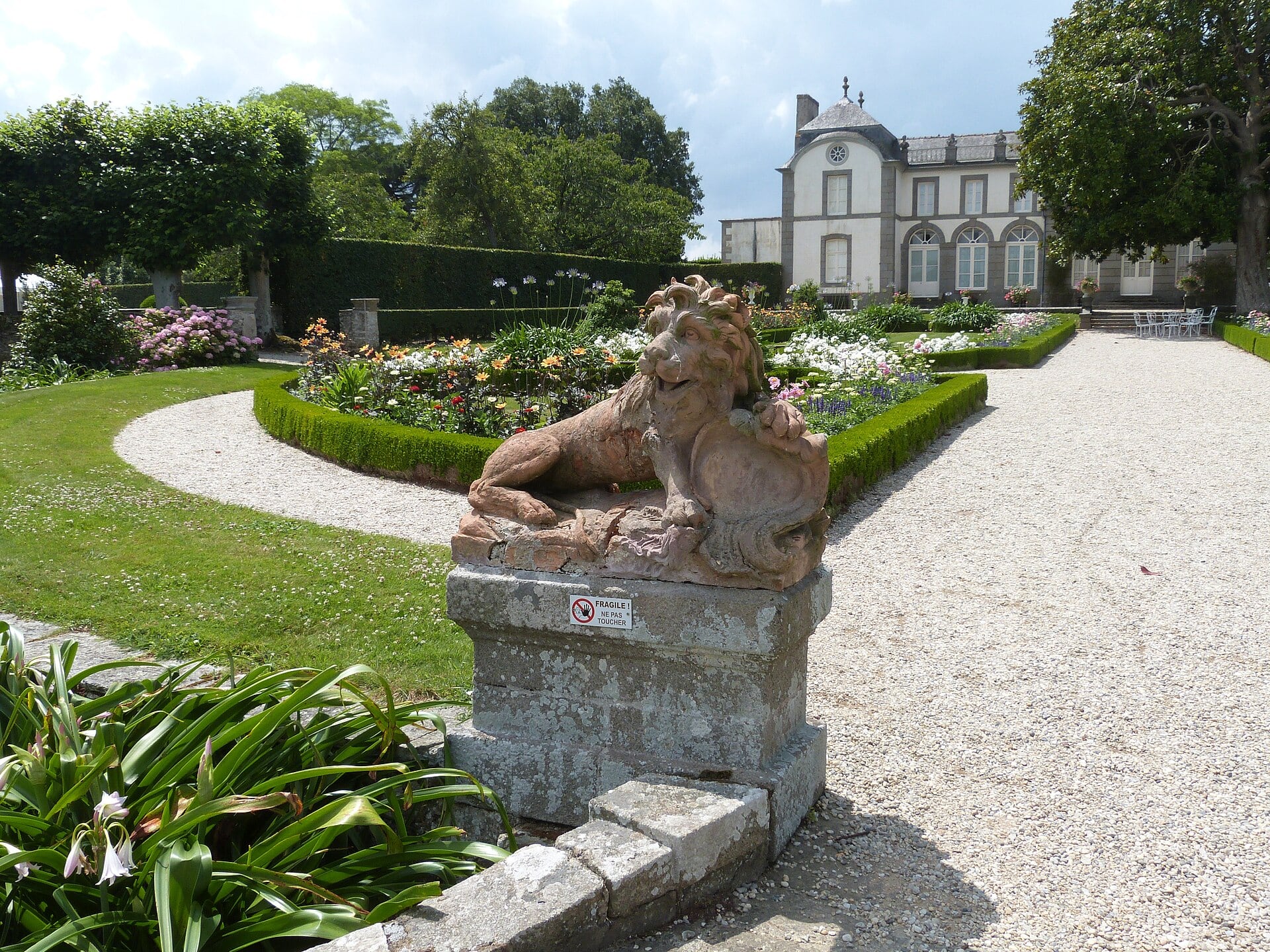 Statue de lion et parterres du jardin à la française du Montmarin devant la demeure