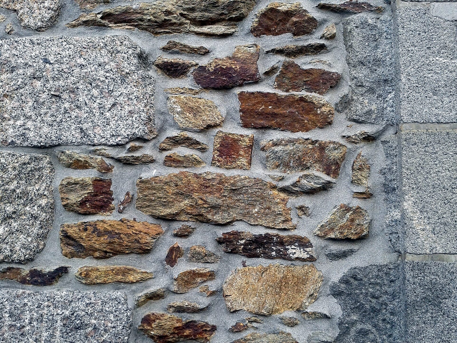 Mur breton mêlant blocs de granite gris et moellons de schiste brun, hourdés au mortier
