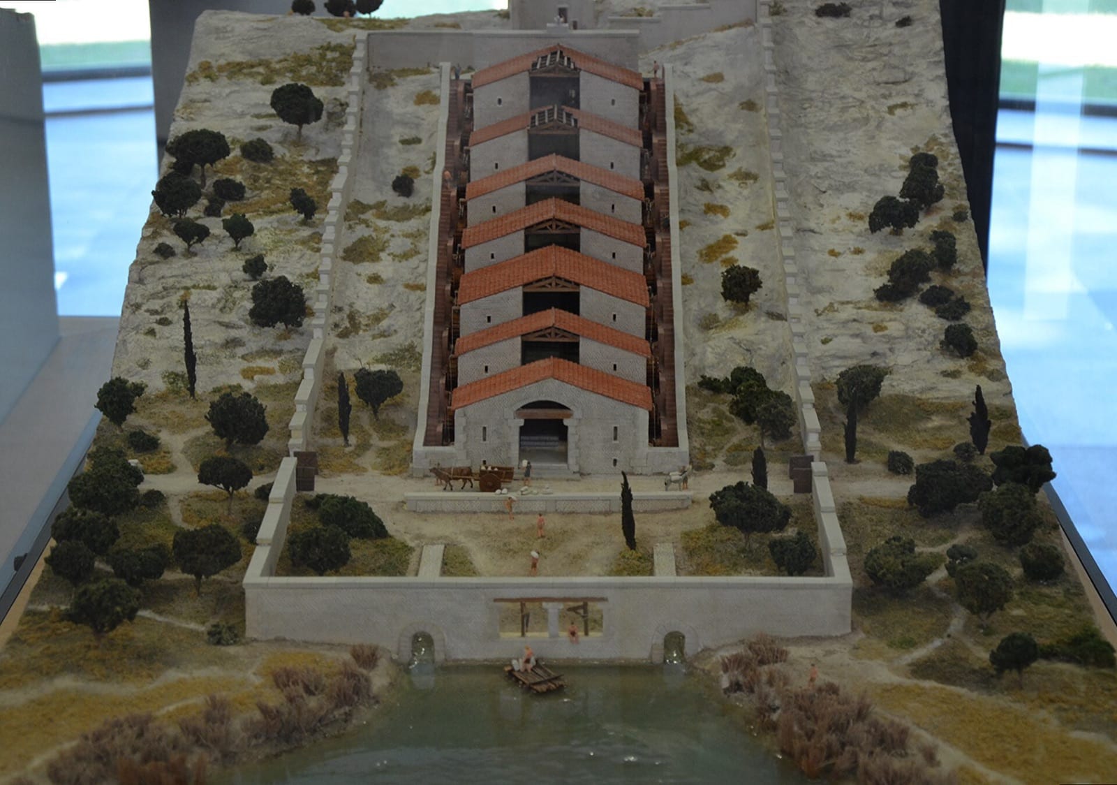 Maquette du complexe meunier romain de Barbegal : deux rangées parallèles de bâtiments couverts de tuiles rouges descendant en cascade le versant, enclos de murs.