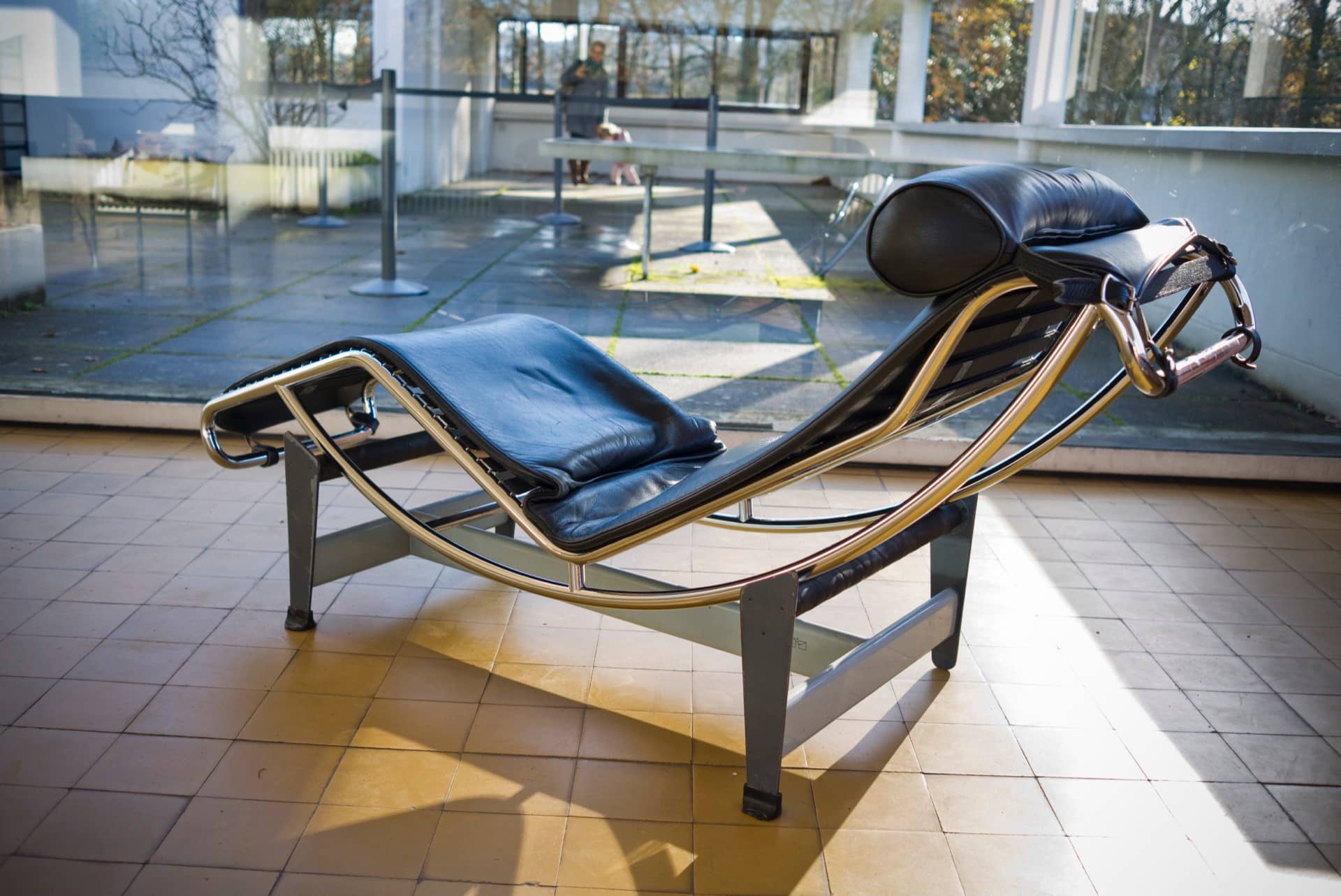 Une chaise longue à structure tubulaire d’acier chromé et cuir noir (modèle LC4) sur la terrasse carrelée de la villa Savoye
