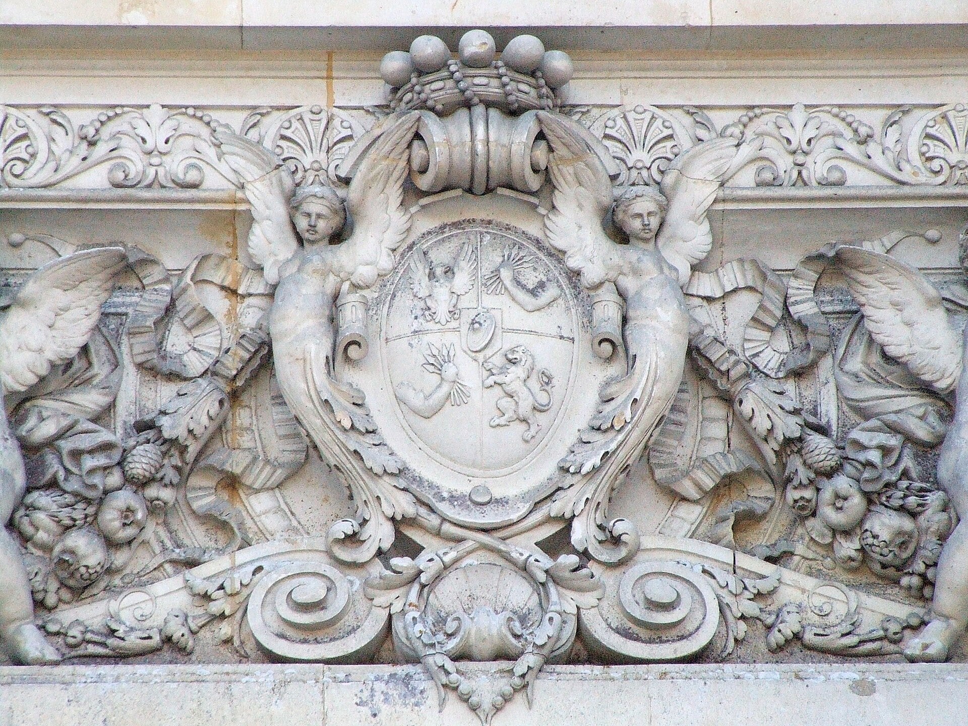 Armoiries des Rothschild sculptées en façade du château de Ferrières : écu à quatre quartiers sous une couronne, encadré de figures ailées et de guirlandes