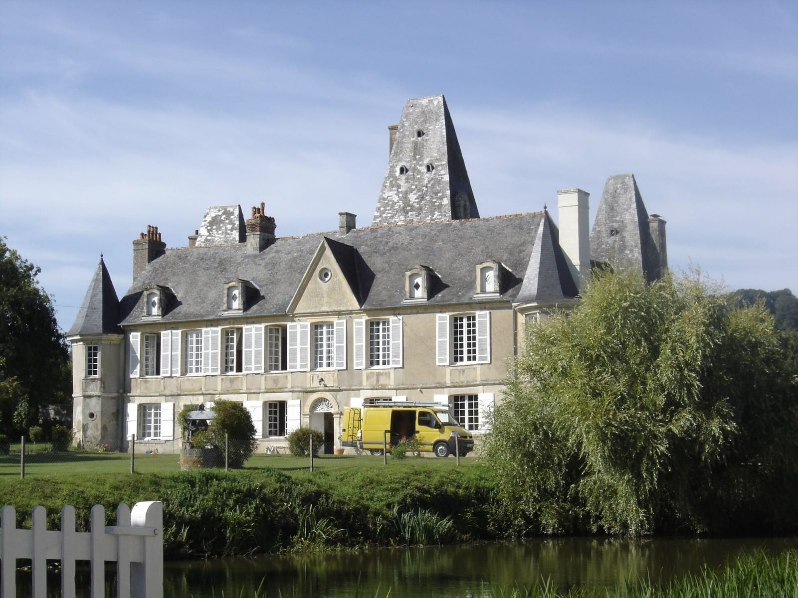 Façade sud du château de Cricqueville-en-Auge vue depuis l’étang ; une baie ronde perce le fronton de la travée centrale