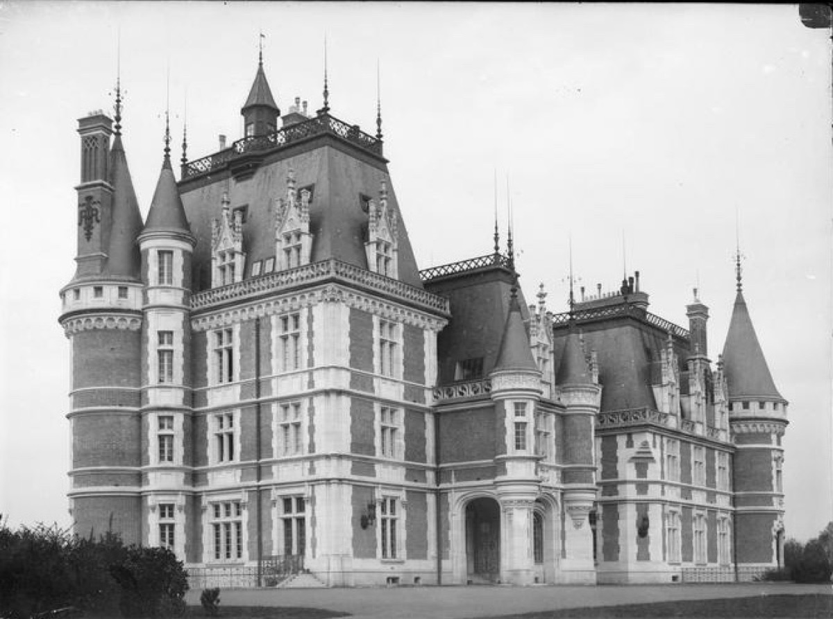 Photographie ancienne en noir et blanc du château de Vouzeron, vaste demeure de brique et de pierre à hauts toits d’ardoise, tourelles à toits coniques, hautes cheminées ouvragées et lucarnes à pinacles