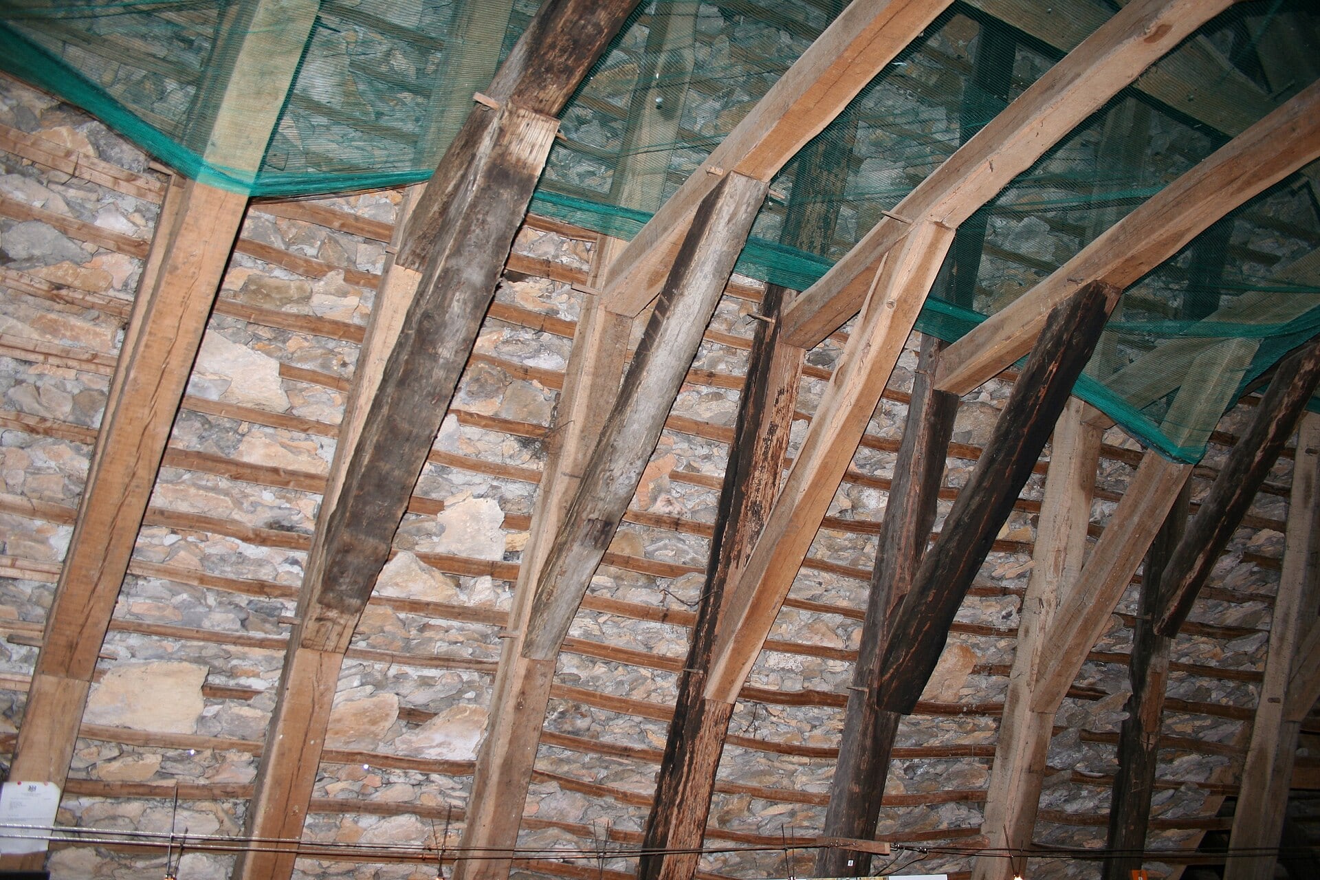 Charpente de chêne et sous-face d’une couverture de lauzes, vue de l’intérieur des combles