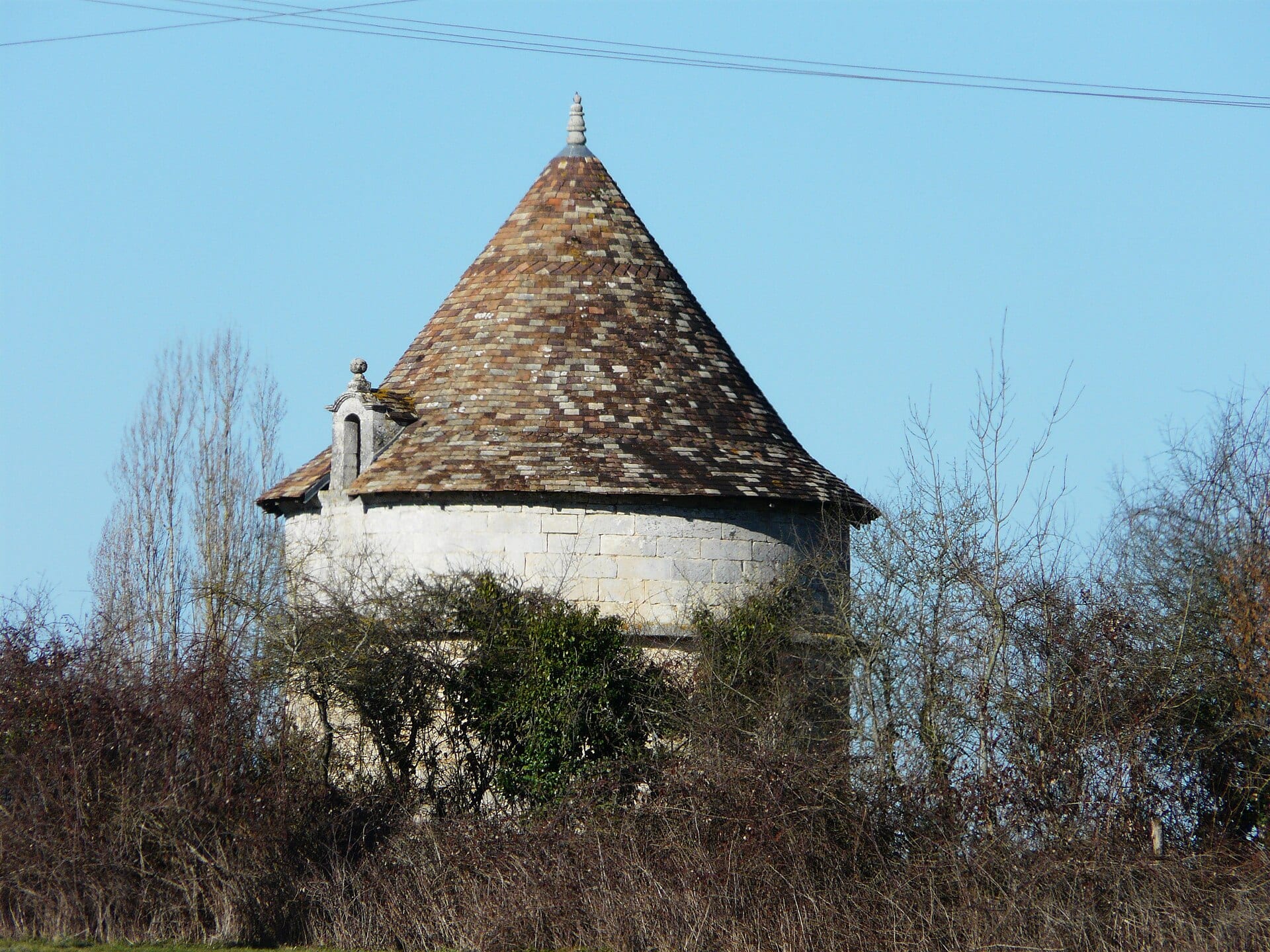 Pigeonnier-tour rond en pierre à toit conique, dans la campagne périgourdine.