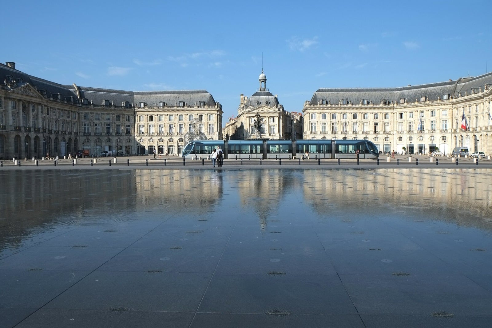 La place de la Bourse à Bordeaux reflétée dans le miroir d’eau, un tramway devant la façade ordonnancée