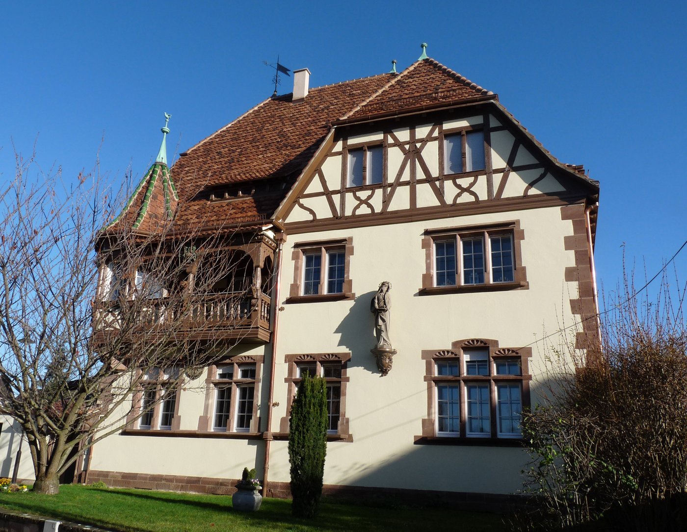 Presbytère catholique alsacien à pans de bois et toiture à forte pente, avec tourelle d’angle et statue de la Vierge en façade, à la Robertsau (Strasbourg).