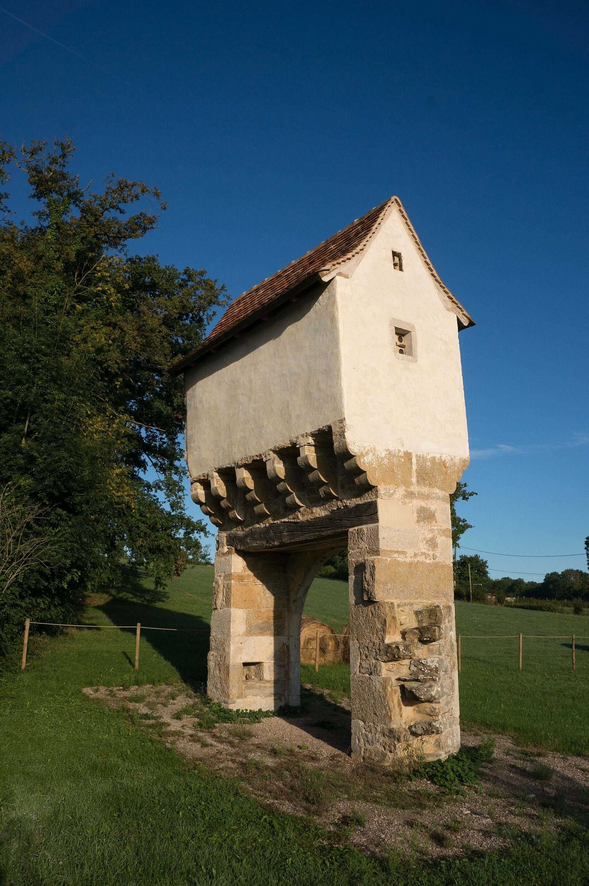 Pigeonnier-porche de pierre porté par des piliers formant arcade, à Lavergne.