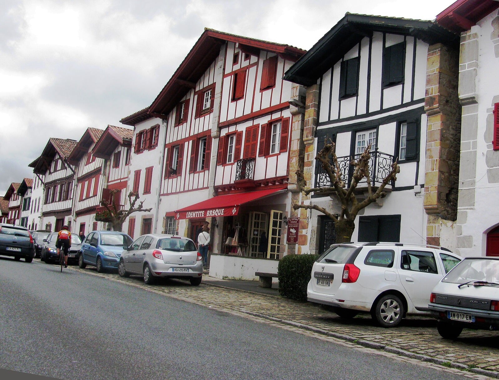 Alignement de maisons labourdines le long de la rue d'Ainhoa, façades blanches à pans de bois rouges et noirs, volets rouges