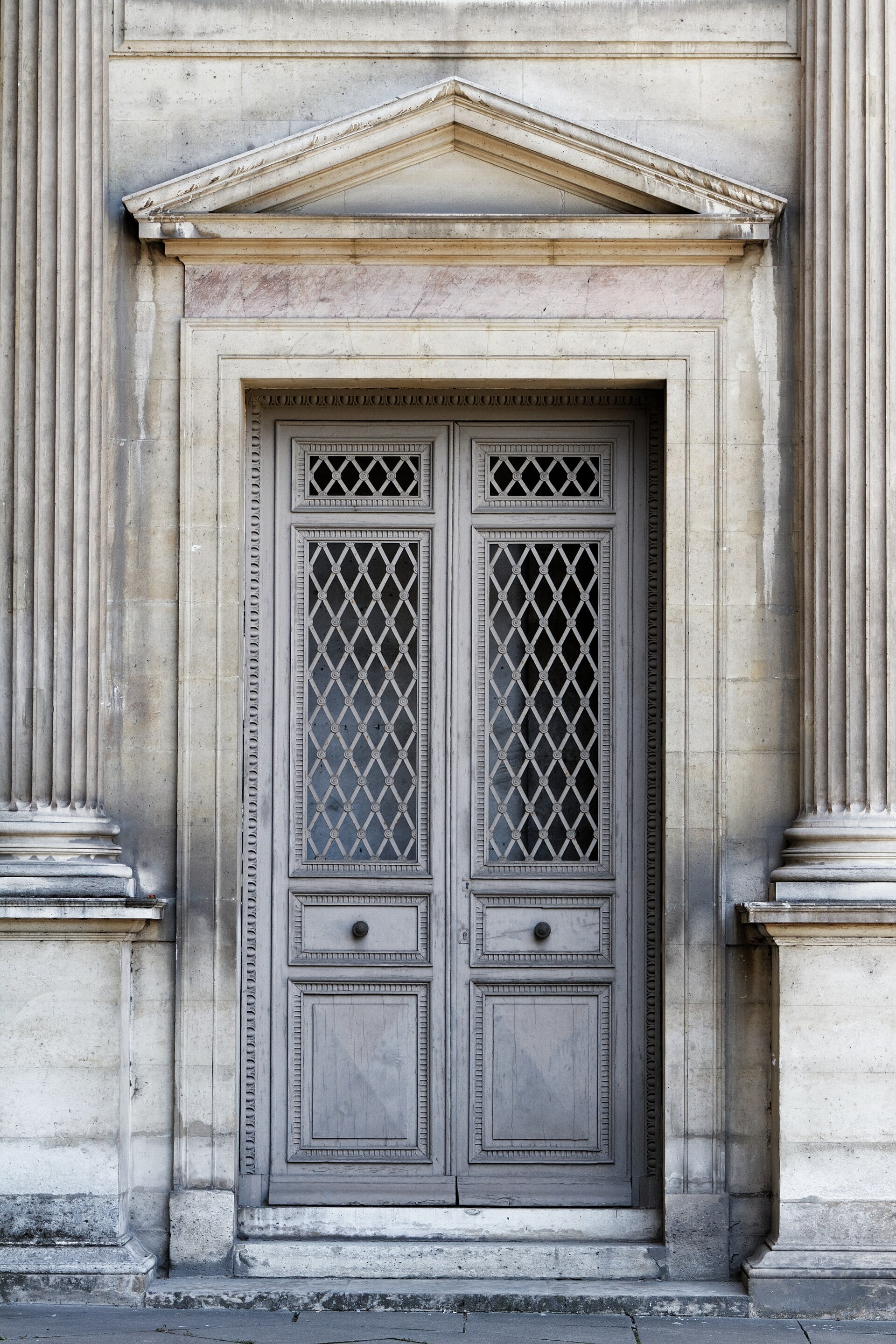 Porte de l’aile Lescot de la cour Carrée du Louvre : encadrement à pilastres cannelés et fronton triangulaire, moulures fines