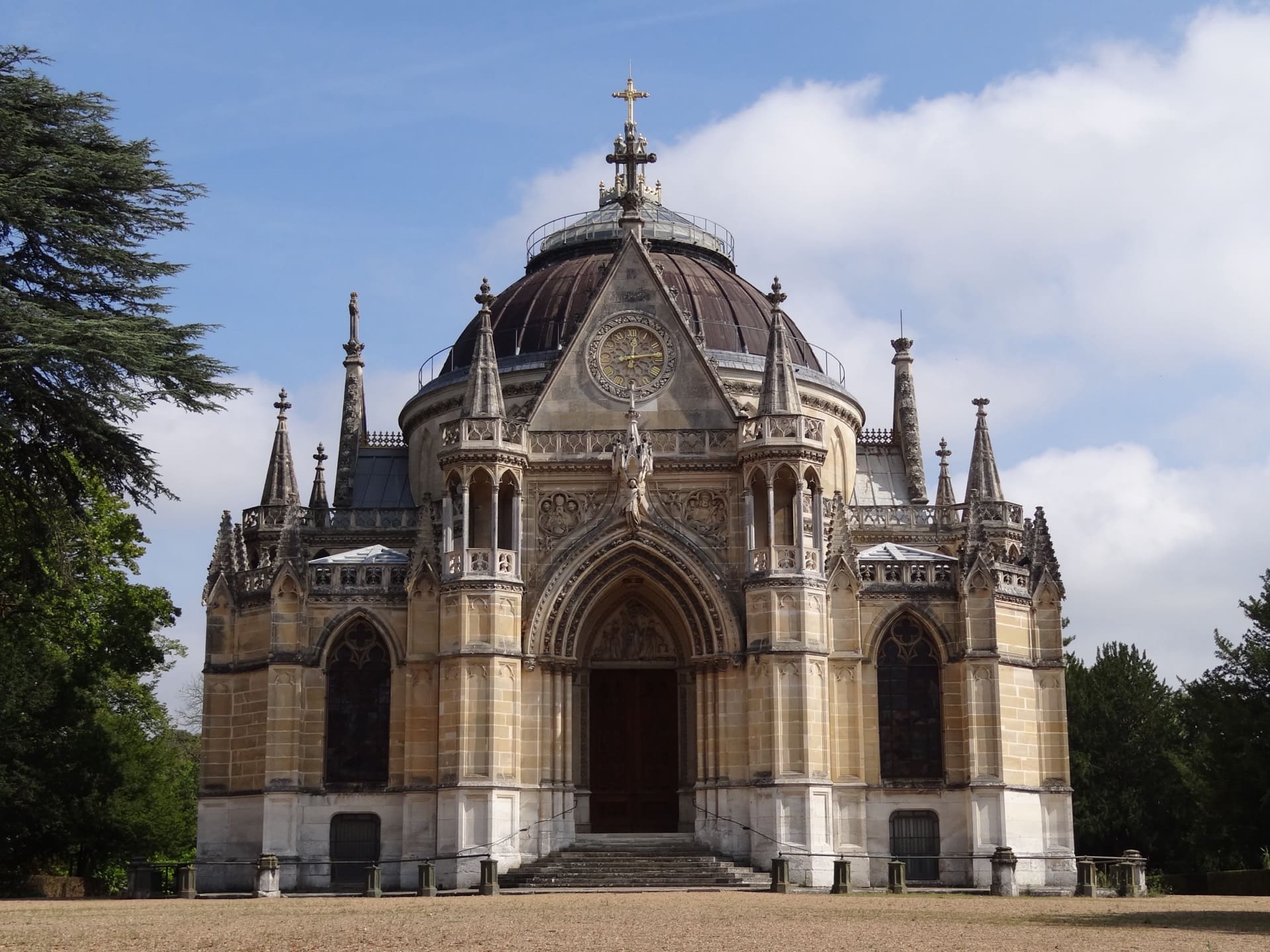 La chapelle royale Saint-Louis de Dreux : façade néogothique à haut portail à gâble, pinacles et clochetons, dôme central couvert surmonté d’une croix, sous un ciel bleu