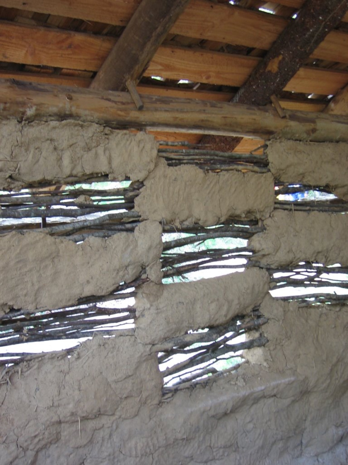 Mur de torchis mis à nu montrant le clayonnage de bois sur lequel la terre fibrée est pressée des deux faces