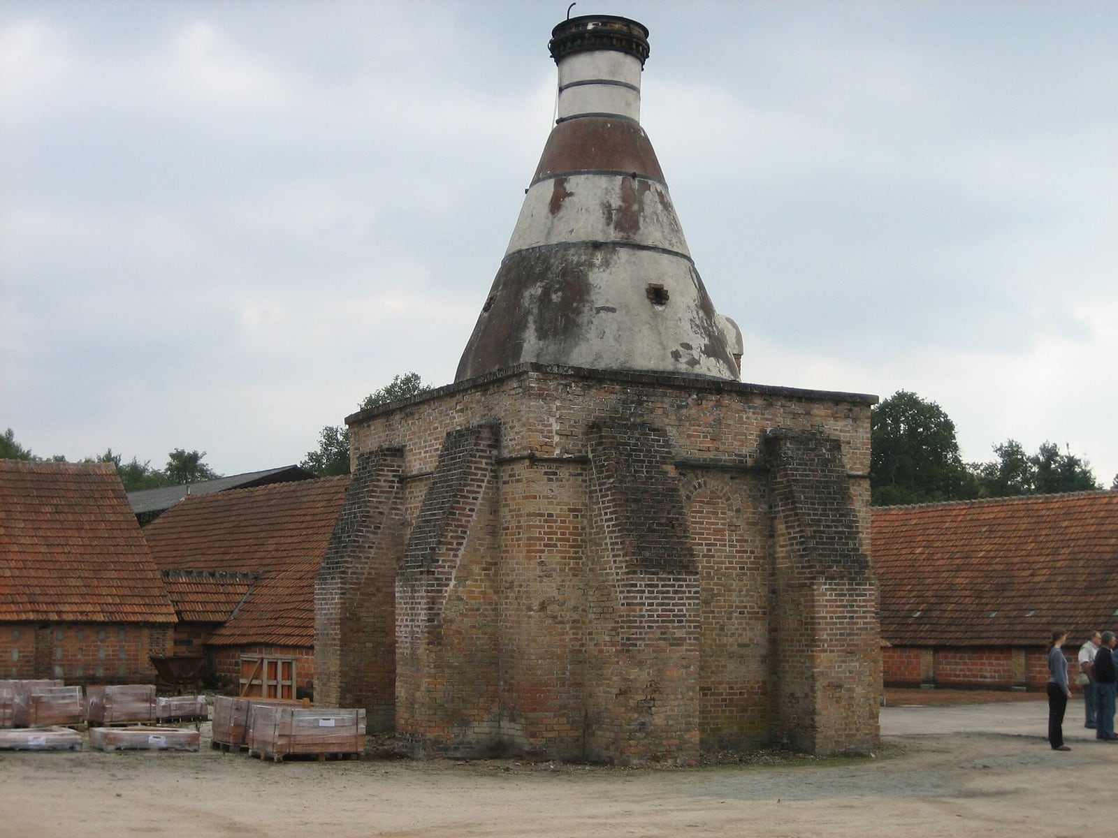Ancien four-bouteille de tuilerie en brique à cheminée conique, dans une cour de séchoirs