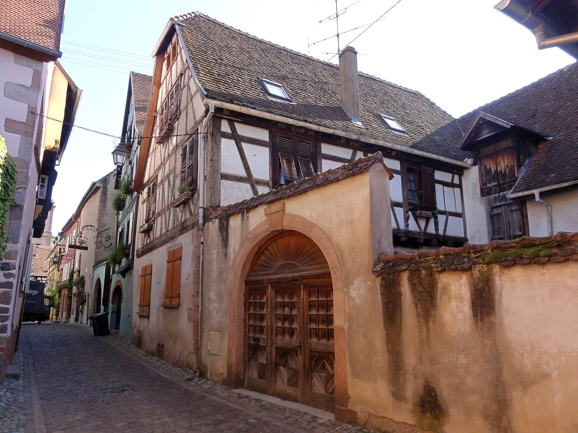 Grande porte cintrée de cave ouvrant sur la rue sous une maison à colombage, à Riquewihr