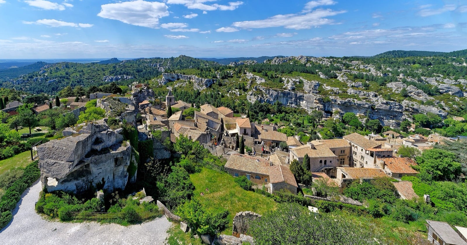 Vue aérienne des Baux-de-Provence, village et clocher sur un éperon rocheux blanc au milieu des Alpilles