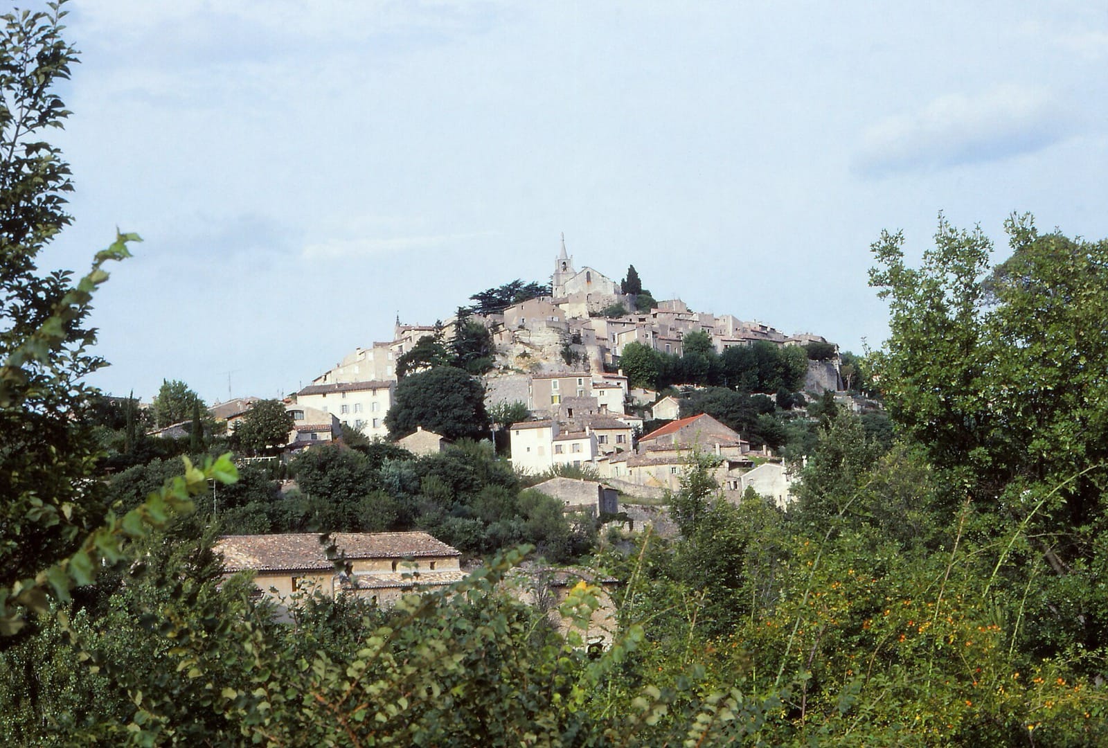 Bonnieux étagé sur sa butte, église et cyprès au sommet, maisons descendant en gradins jusqu’à la campagne