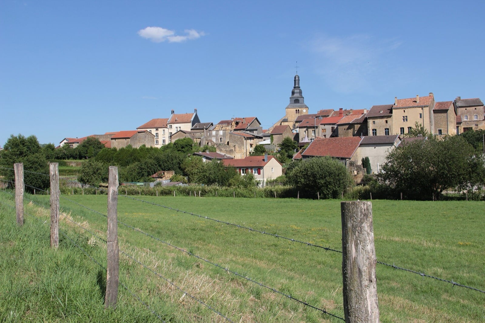 Marville vu depuis la campagne : le village étiré en une seule masse bâtie le long de la crête, clocher au centre