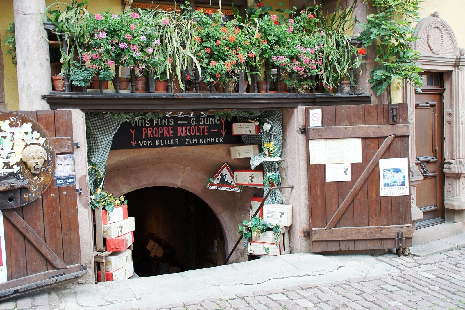 Porte de cave en plein cintre creusée dans le rocher, accessible de plain-pied depuis une rue pavée