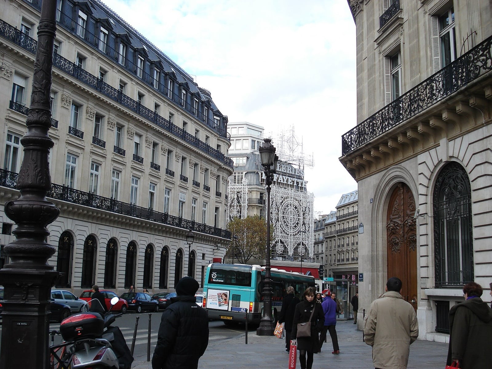 Rue parisienne bordée d’immeubles haussmanniens aux combles mansardés sombres coiffés de zinc